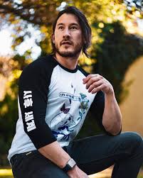 A person in a casual outfit sits outside, with trees and sunlight softly illuminated in the background.