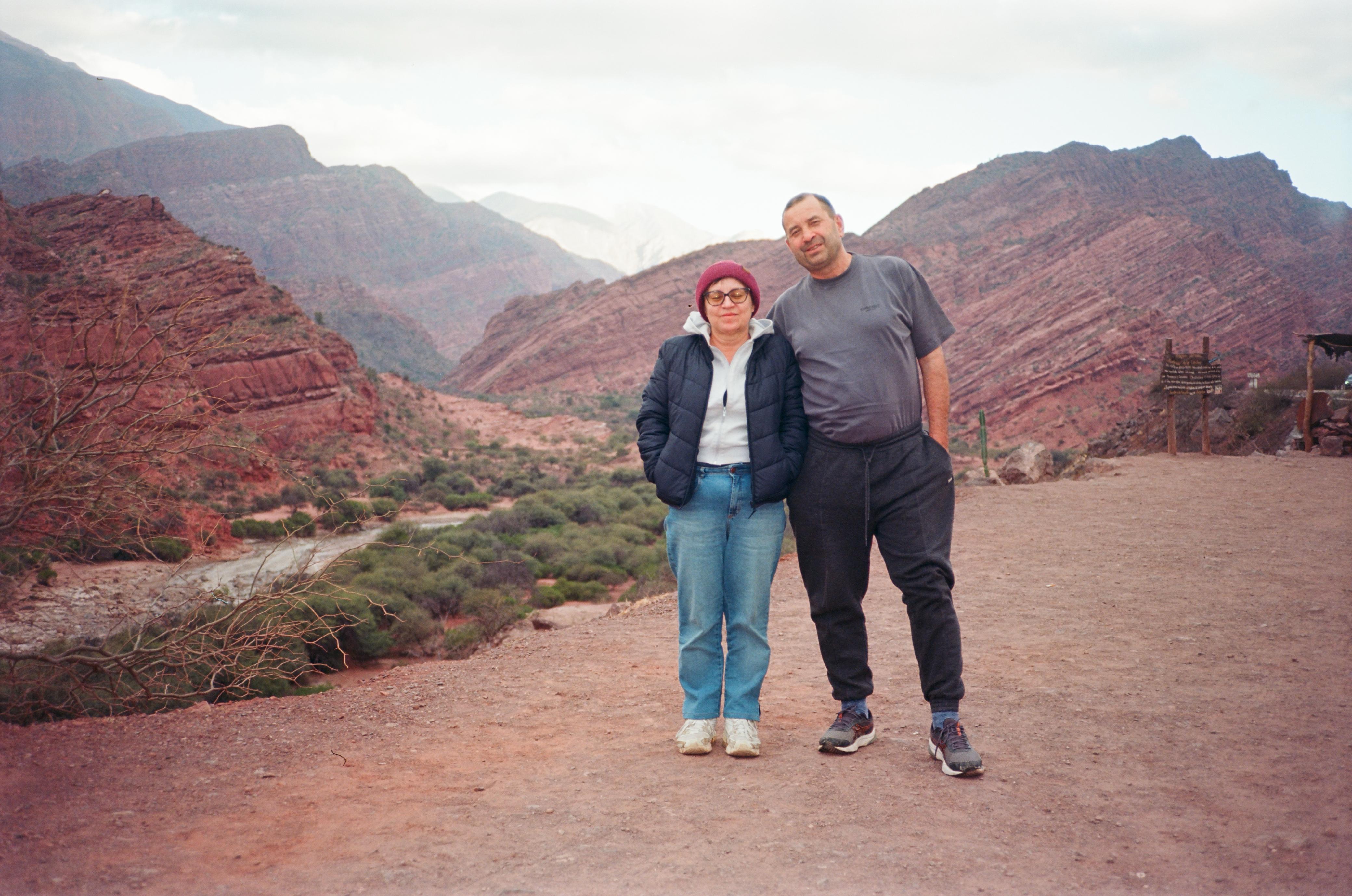 Mujer sentada sobre un tronco frente a una cascada doble en un bosque frondoso de Argentina.