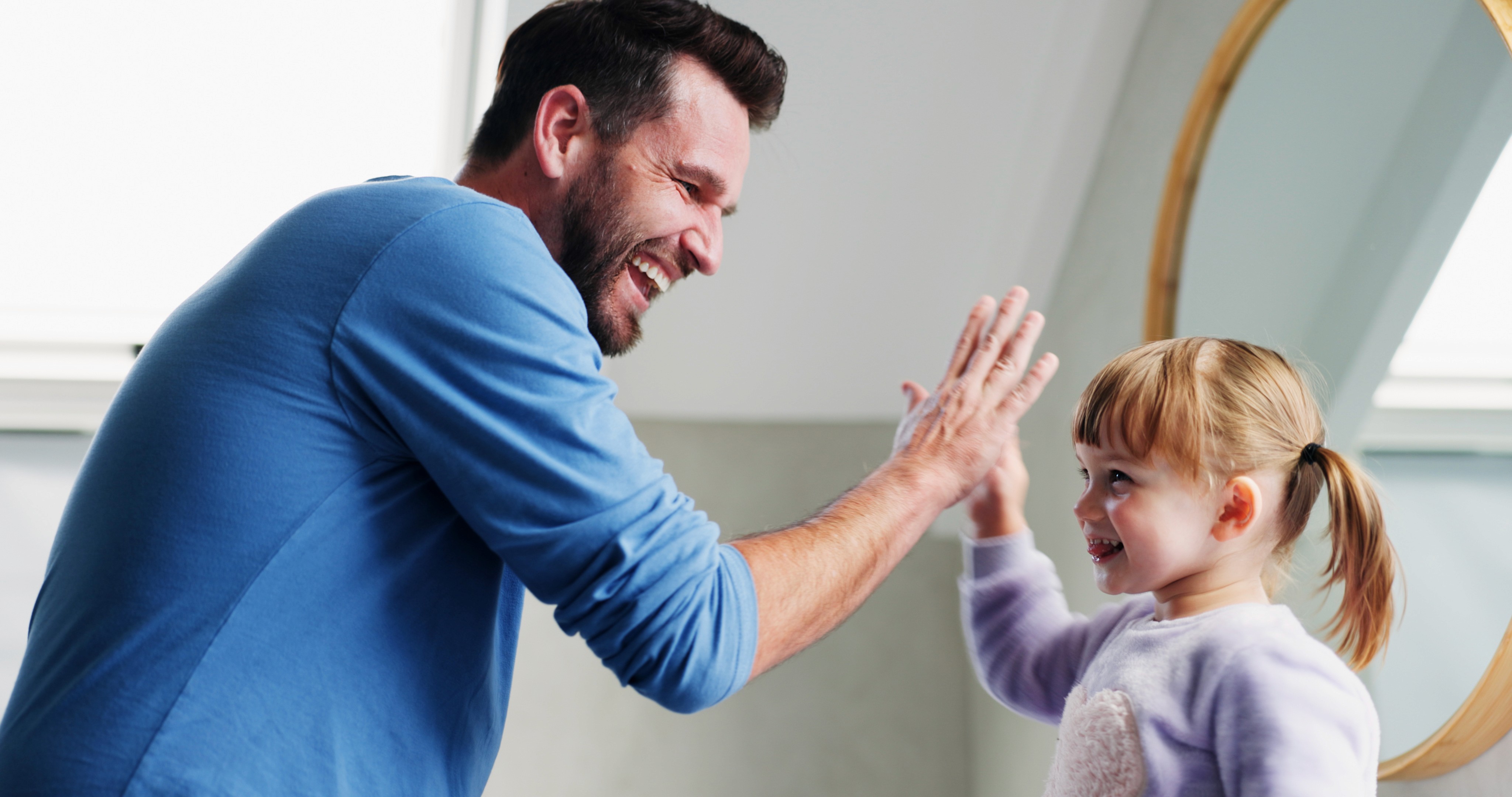 Father and young daughter laughing and giving a high five, representing the positive outcome of child custody and family law cases at Lamb & Lamb, P.C. in Essex County, MA