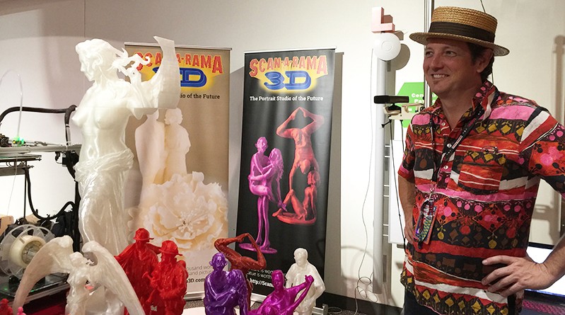a man with a red and colorful pink shirt in an exhibition gallery with vividly colored sculptures