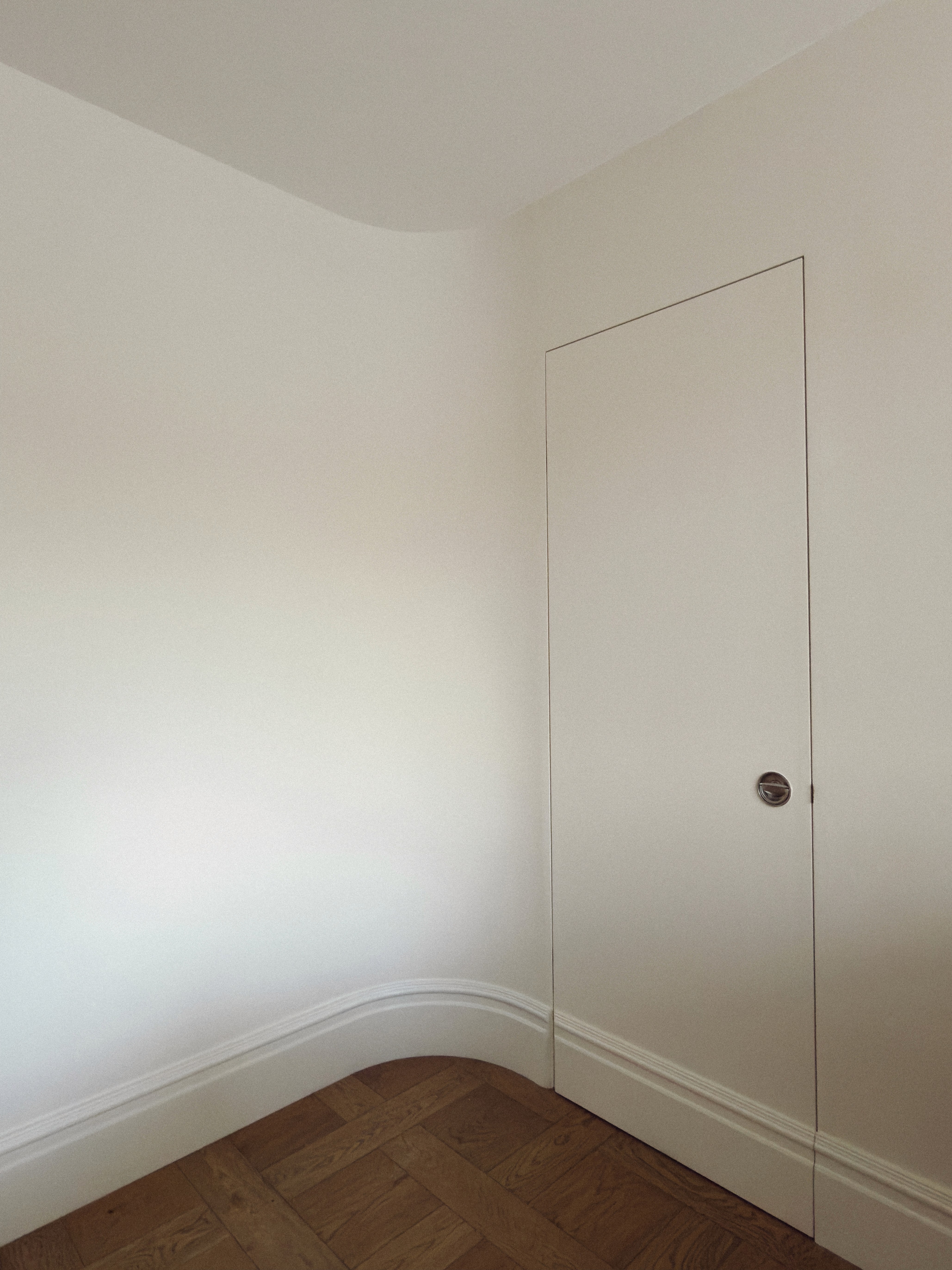 Minimal white bedroom corner with flush door detail