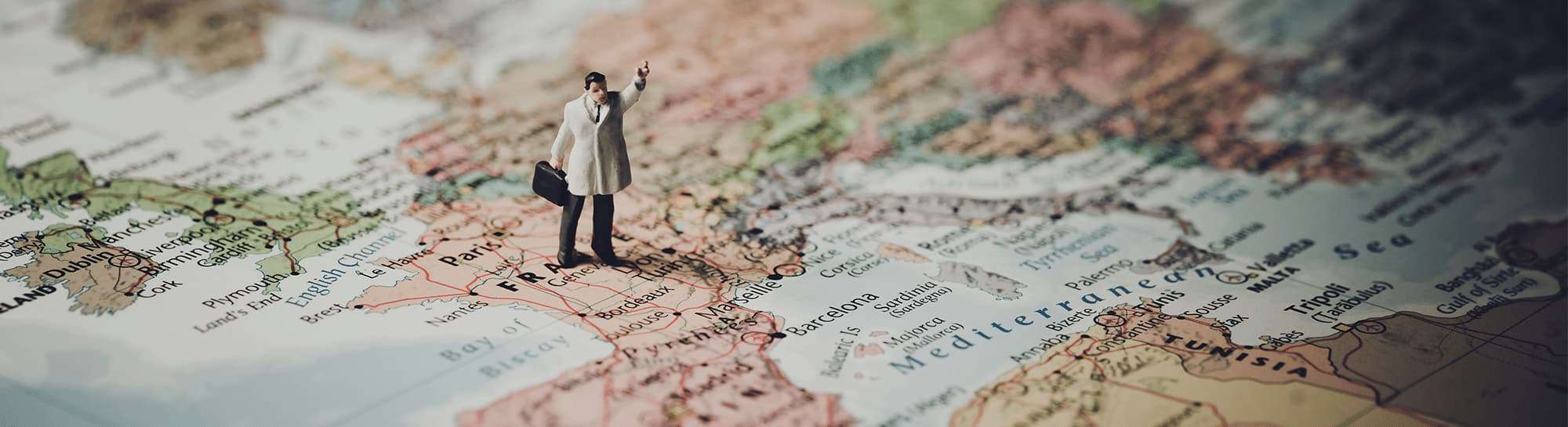 Miniatura di un uomo su una mappa d'Europa che punta in avanti, rappresentando un'esperienza utente personalizzata nell'e-commerce internazionale.