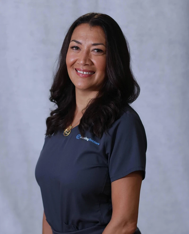 Picture of Ana Anzola. A woman with long dark hair smiles, wearing a navy blue shirt, set against a light gray background.
