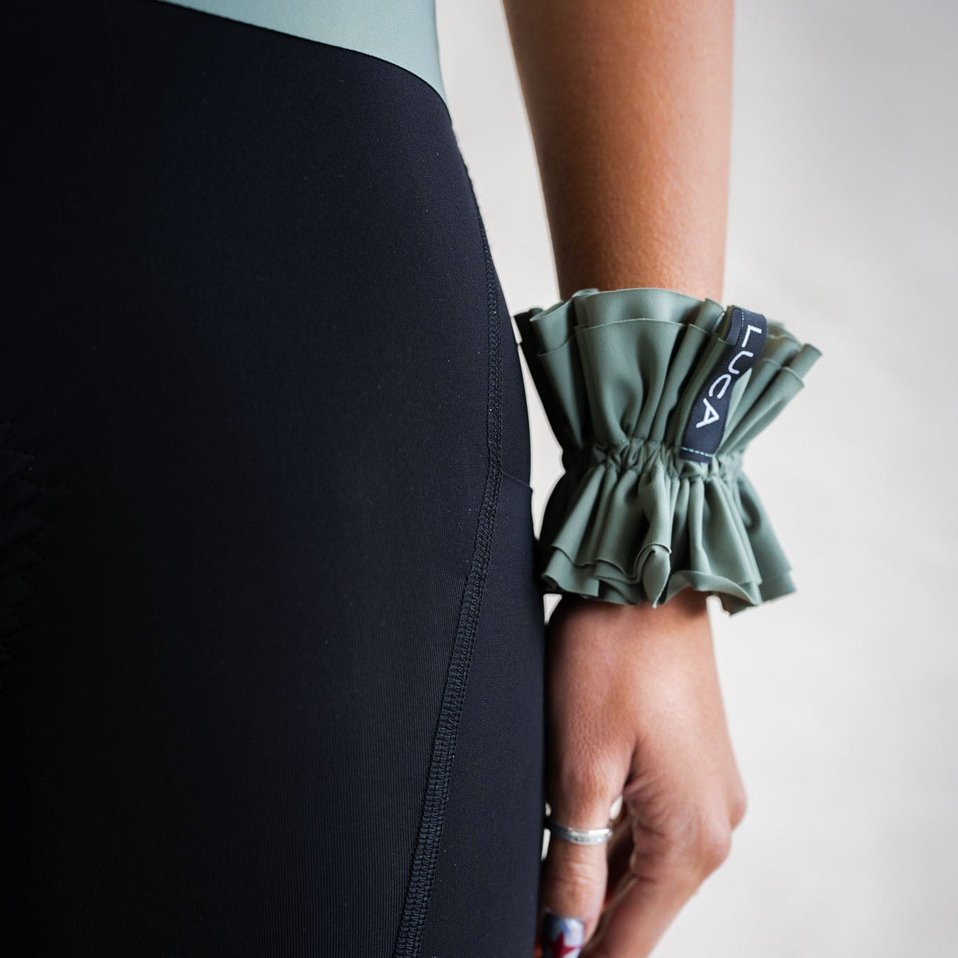 LUCA Uplift scrunchie in matcha worn on wrist next to cycling shorts