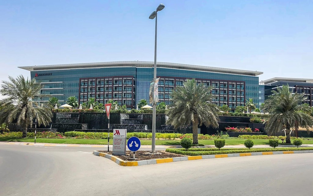 Office building in Dubai's Al Forsan Village, surrounded by palm trees under a clear blue sky.