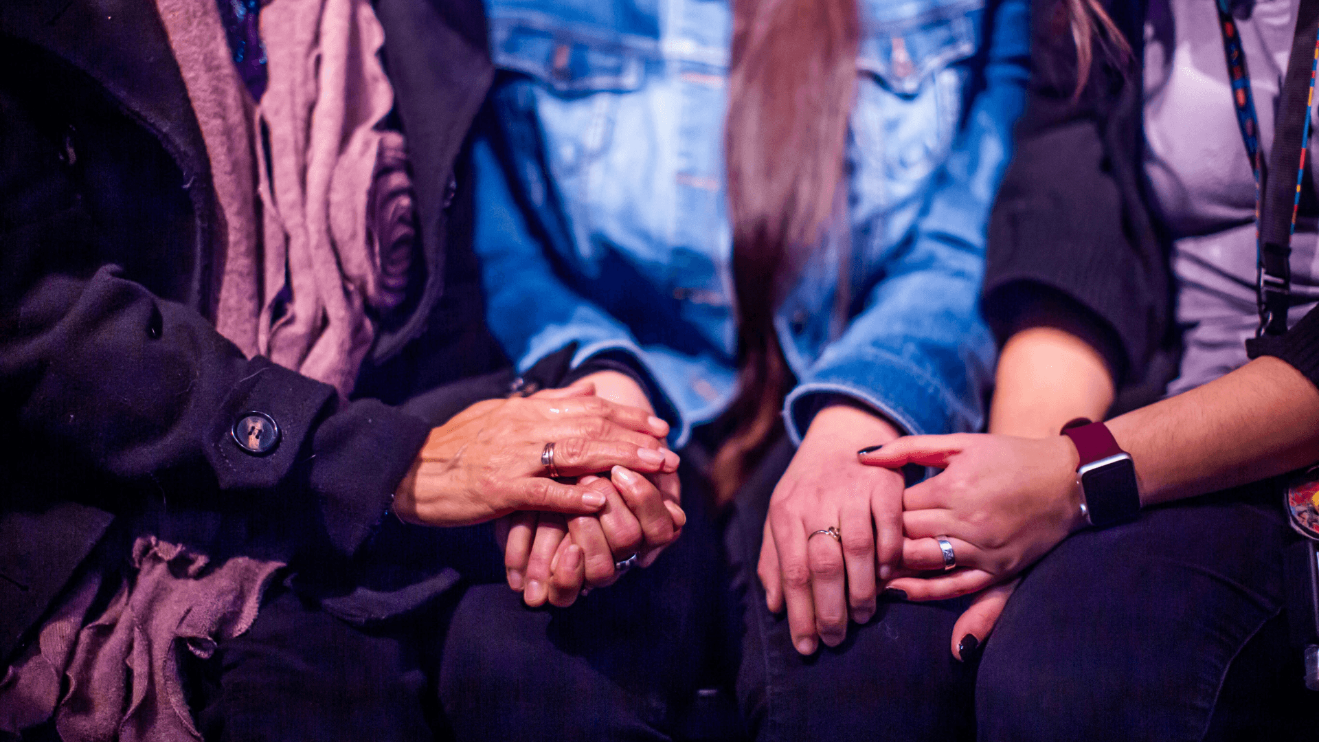 cropped photo of three women holding each others hands in support
