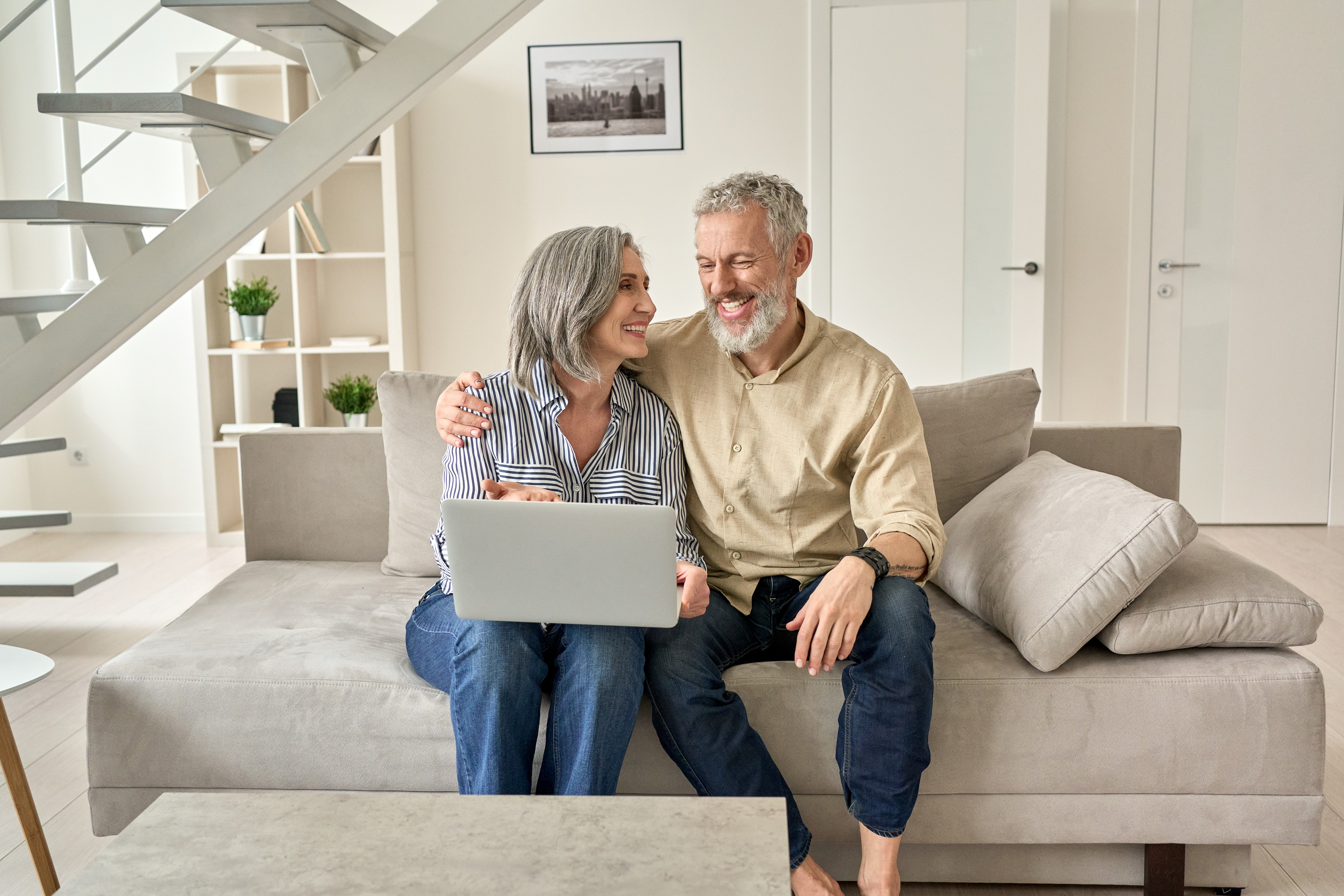 Happy couple sitting on couch in their home.