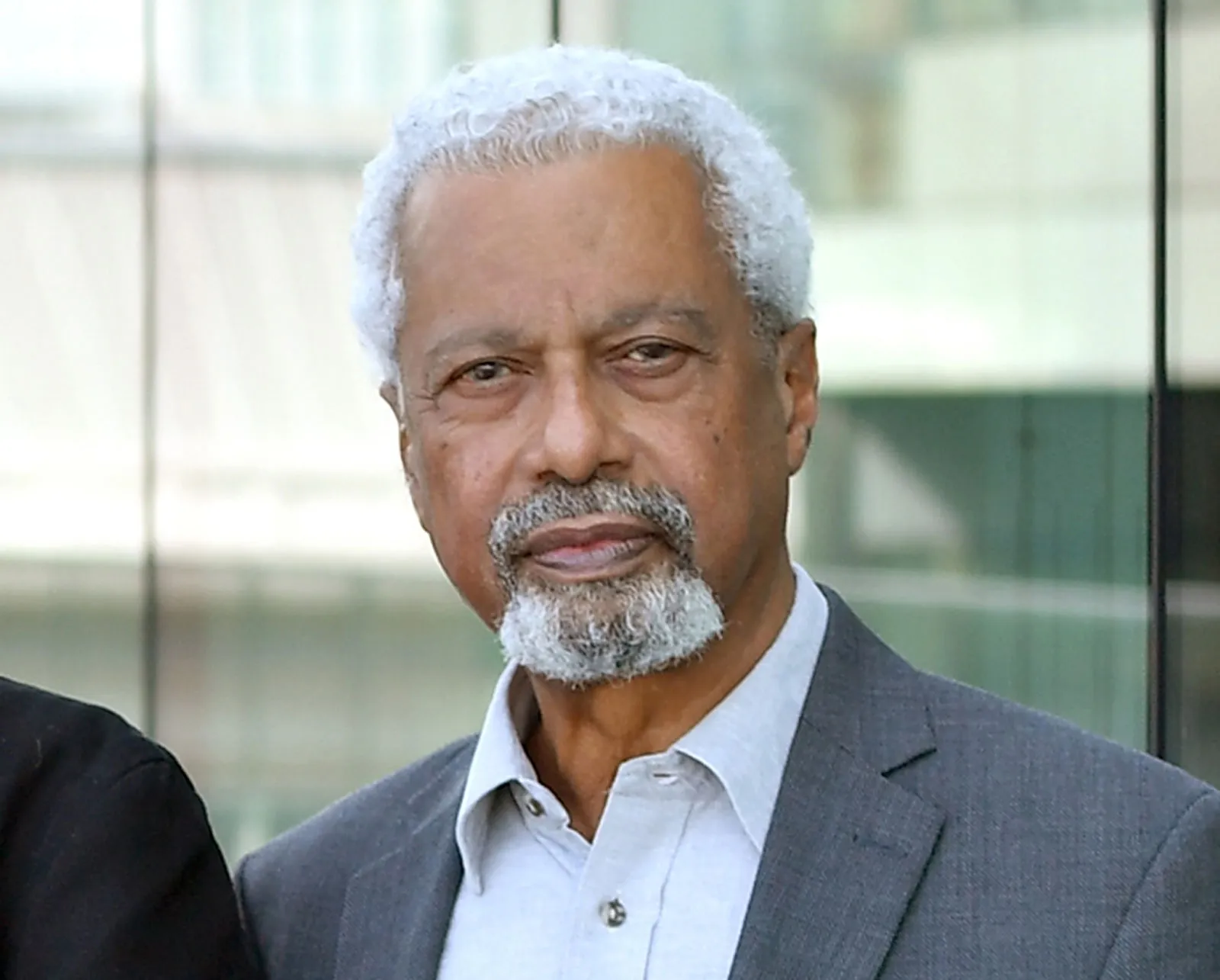 Smiling woman in beige linen outfit standing indoors with plants and books in the background.