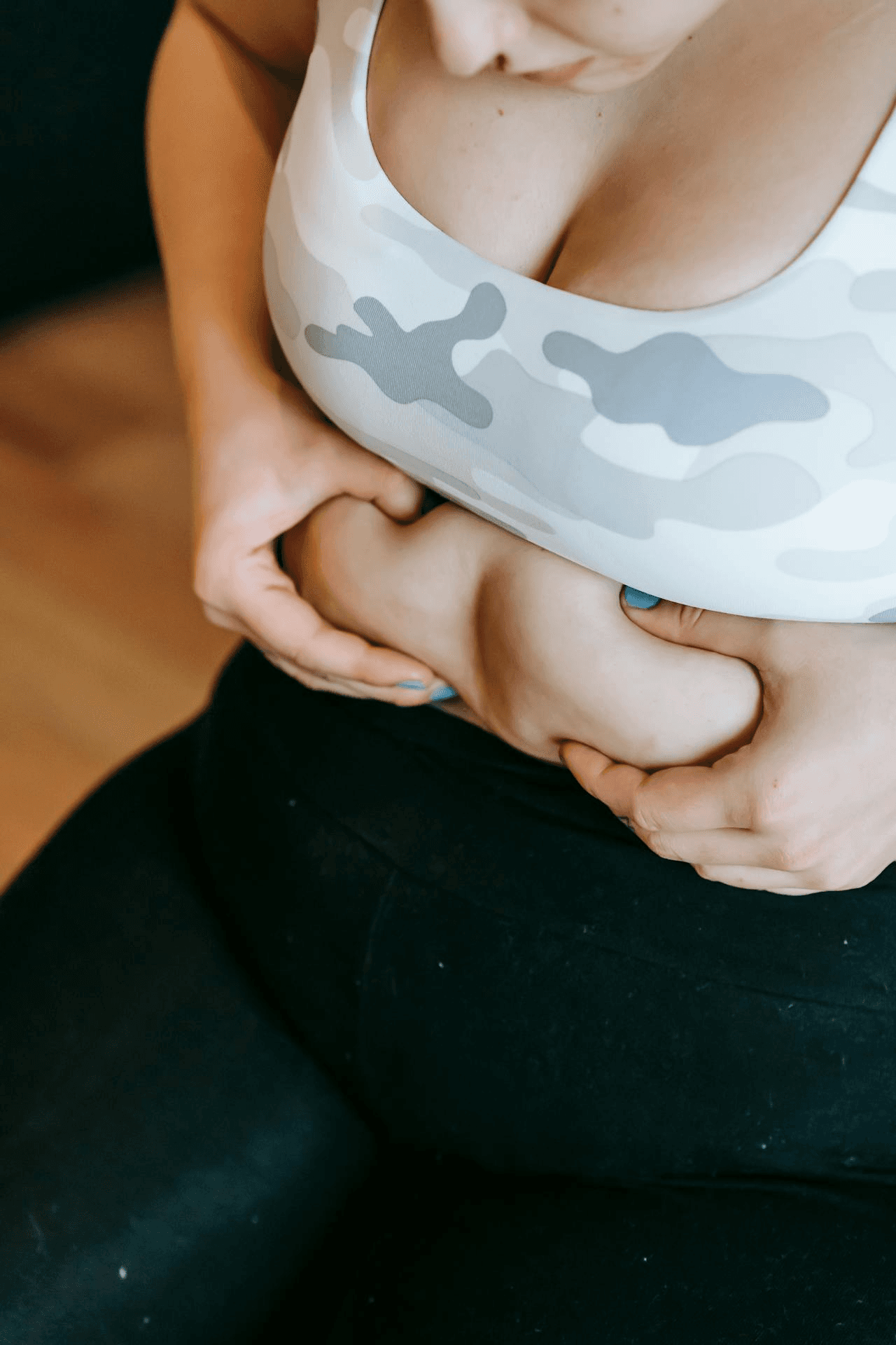 A young woman grabs her abdominal fat.