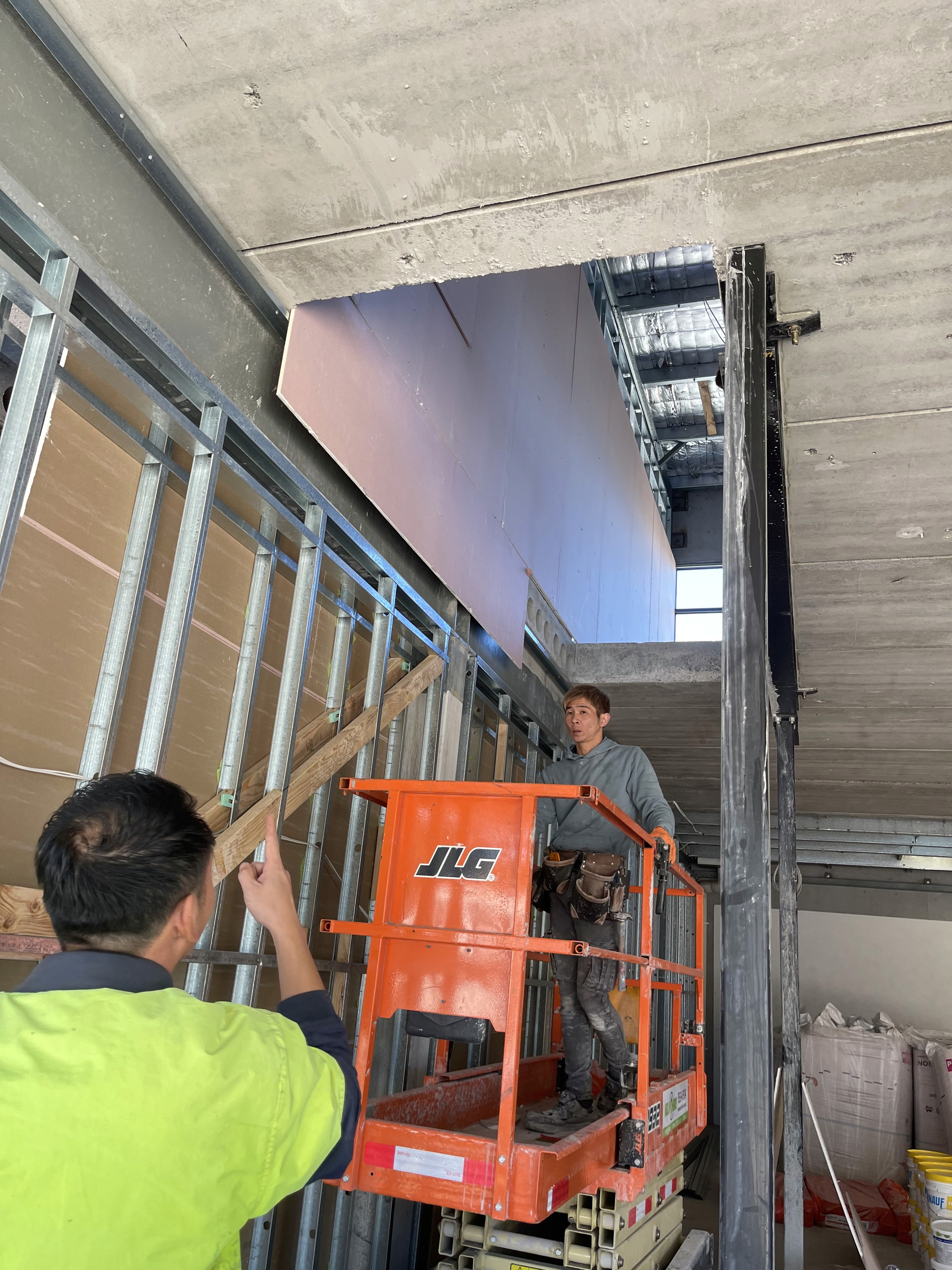 A modern house with large windows and a flat roof, surrounded by greenery against a clear blue sky.