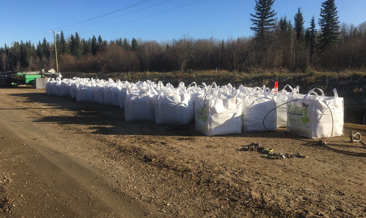 Row of filled sediment control bags staged along the roadside at Carrot Creek Tower Road, Yellowhead County, Alberta