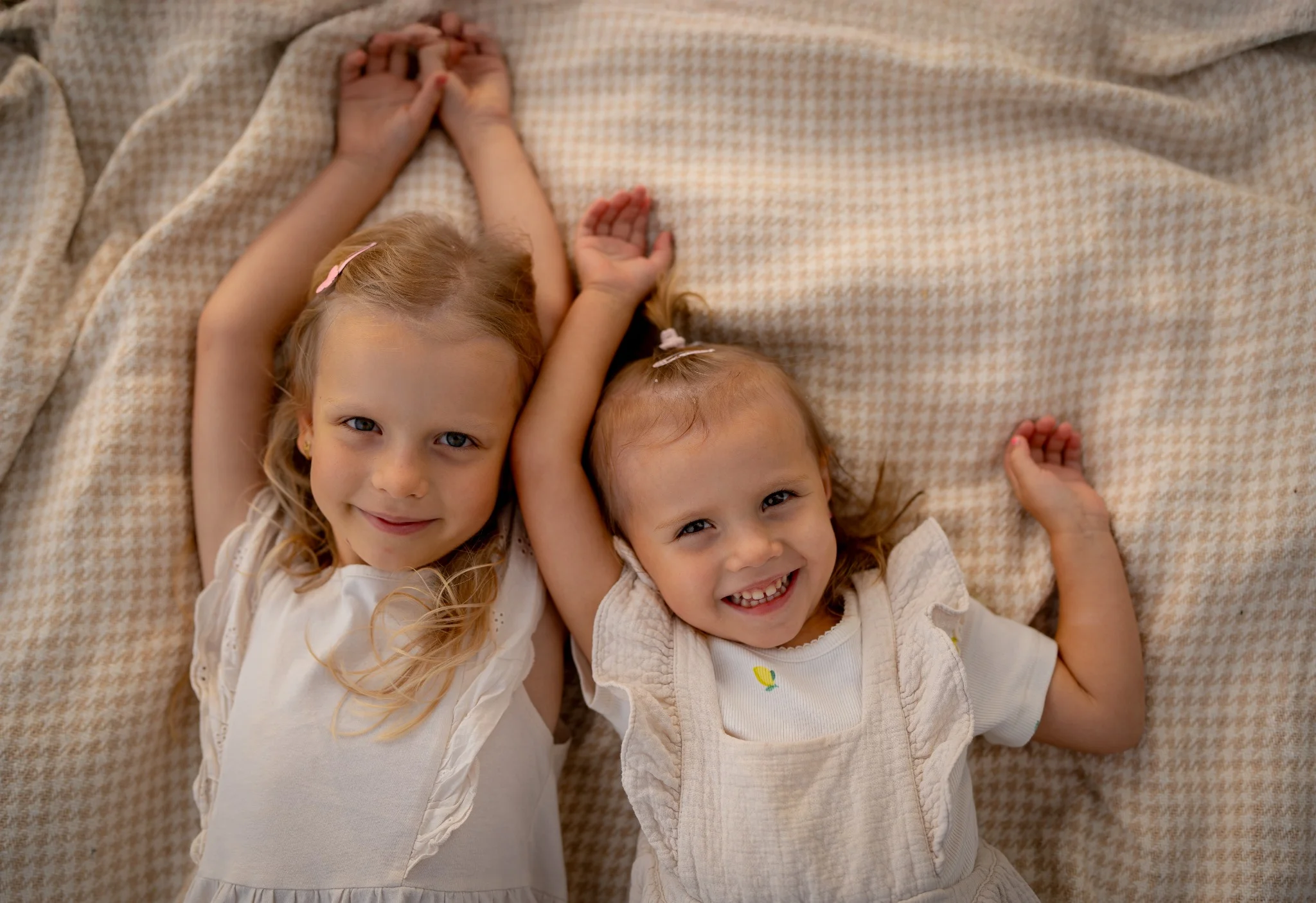  Na zdjęciu widnieje rodzina podczas pikniku na świeżym powietrzu, obok spokojnego jeziora. Składa się z mężczyzny, kobiety i małego dziecka. Mężczyzna ma na sobie jasnoniebieską koszulę i krótkie spodenki, siedzi z przodu i trzyma dziecko na kolanach. Kobieta, ubrana w kolorową sukienkę i kapelusz, siedzi obok i uśmiecha się, patrząc na dziecko. Sceneria jest zielona, z dużą ilością trawy i drzew w tle. Całość tworzy spokojną i sielankową atmosferę.