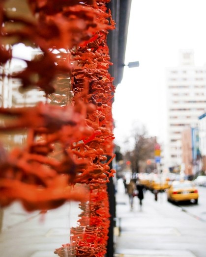 A photo of some orange pieces of plastic on a glass wall and a street with cars.