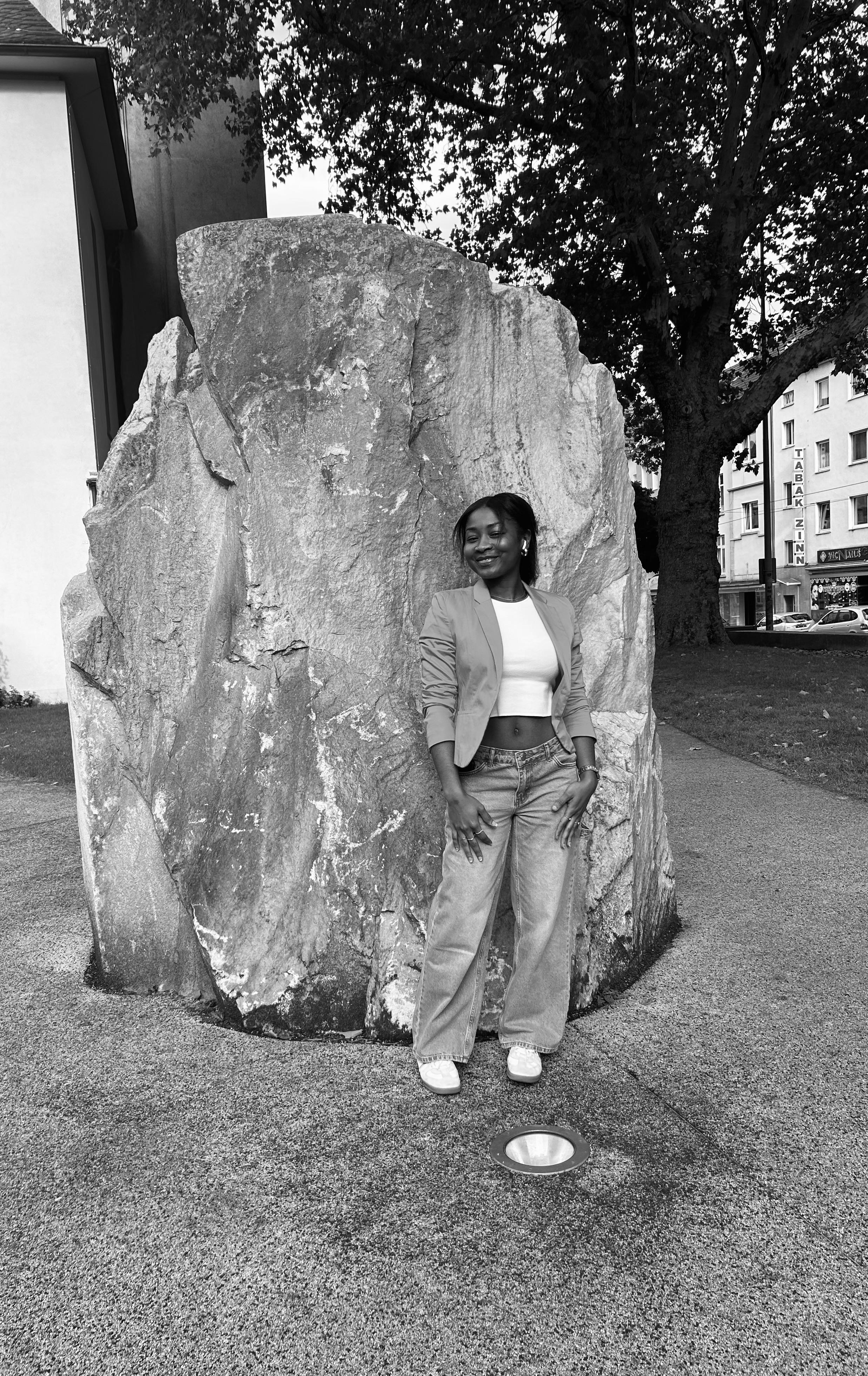 Maybell, next to a large, rock-like structure in a black-and-white outdoor setting