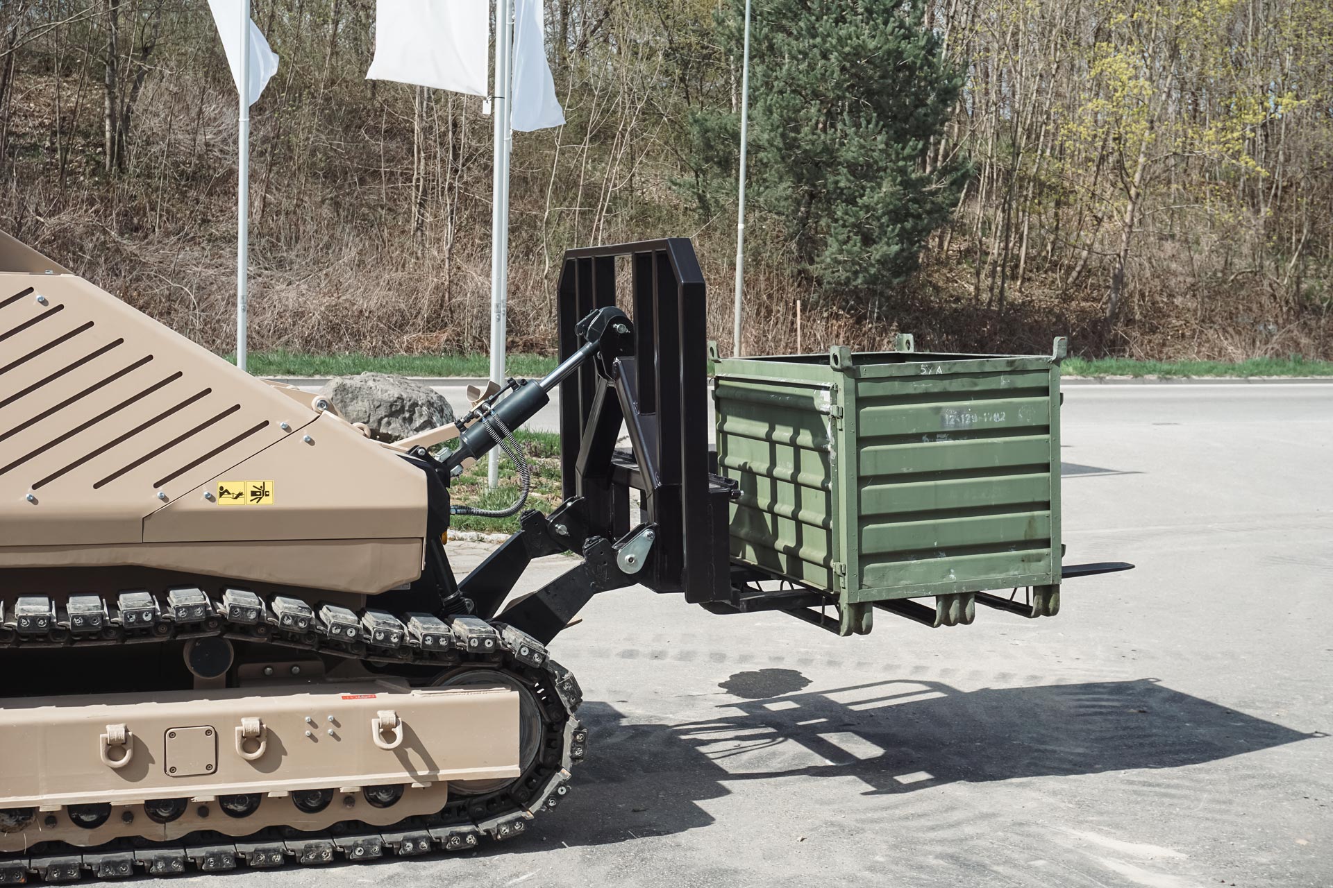 GCS-200 remote-controlled platform with pallet fork attachment safely transporting a container during ammunition management operations.
