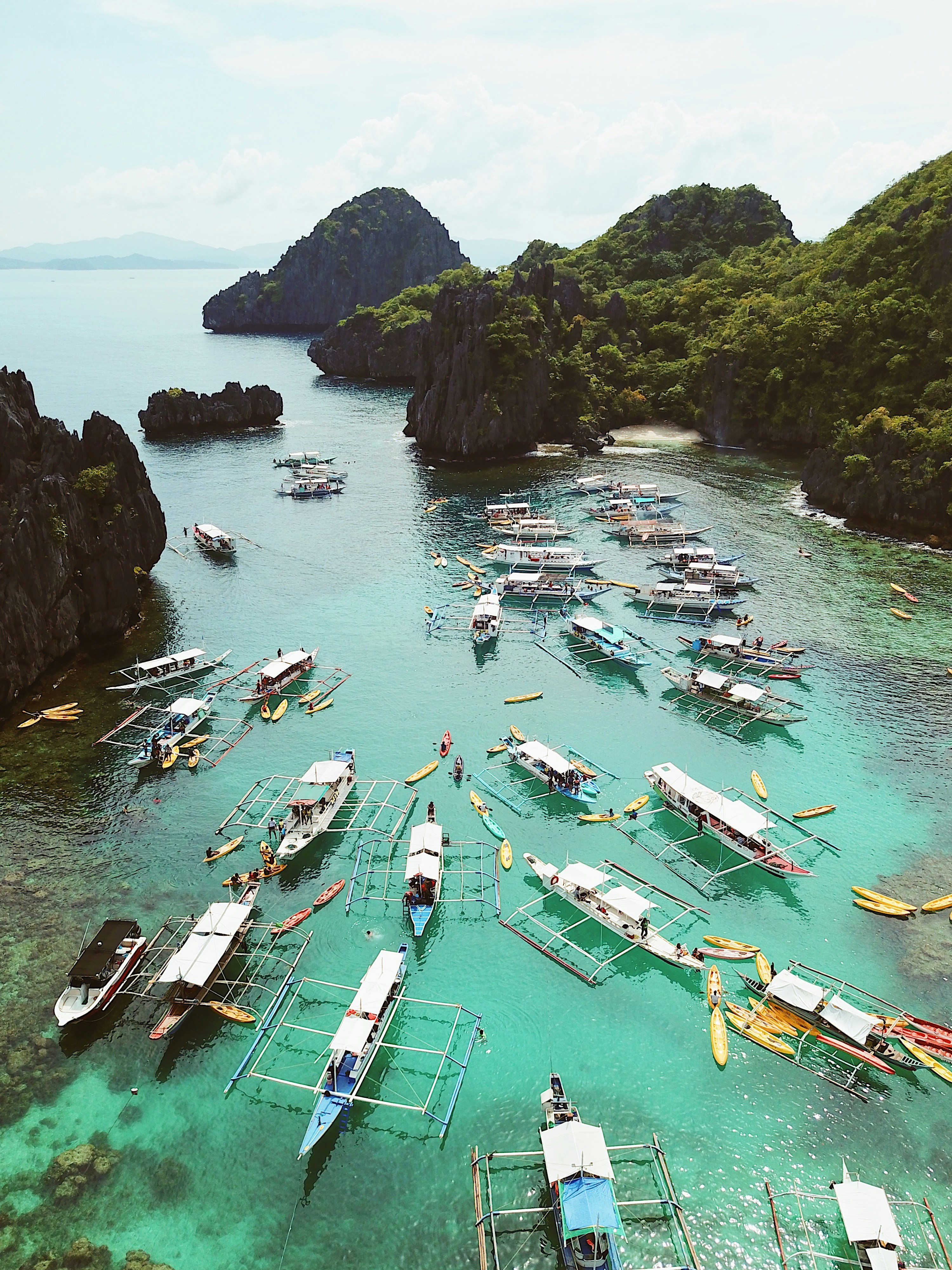 a spectrum of colourful boats on a lake, gazing at distant islands