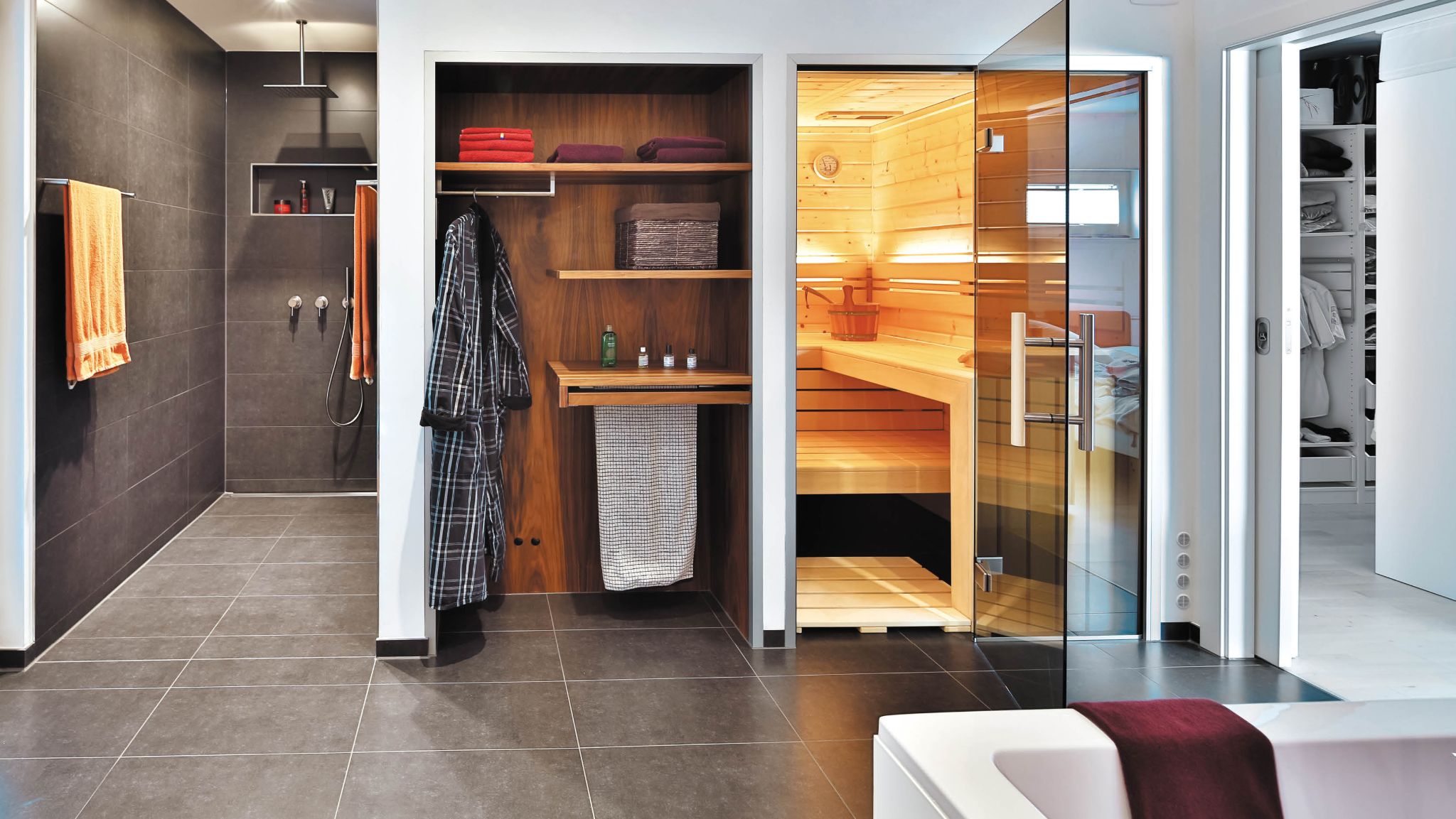 Luxuriöses Badezimmer mit begehbarer Dusche, offener Garderobe, einer Holzsauna und einem Badezimmer in stilvollem Design.