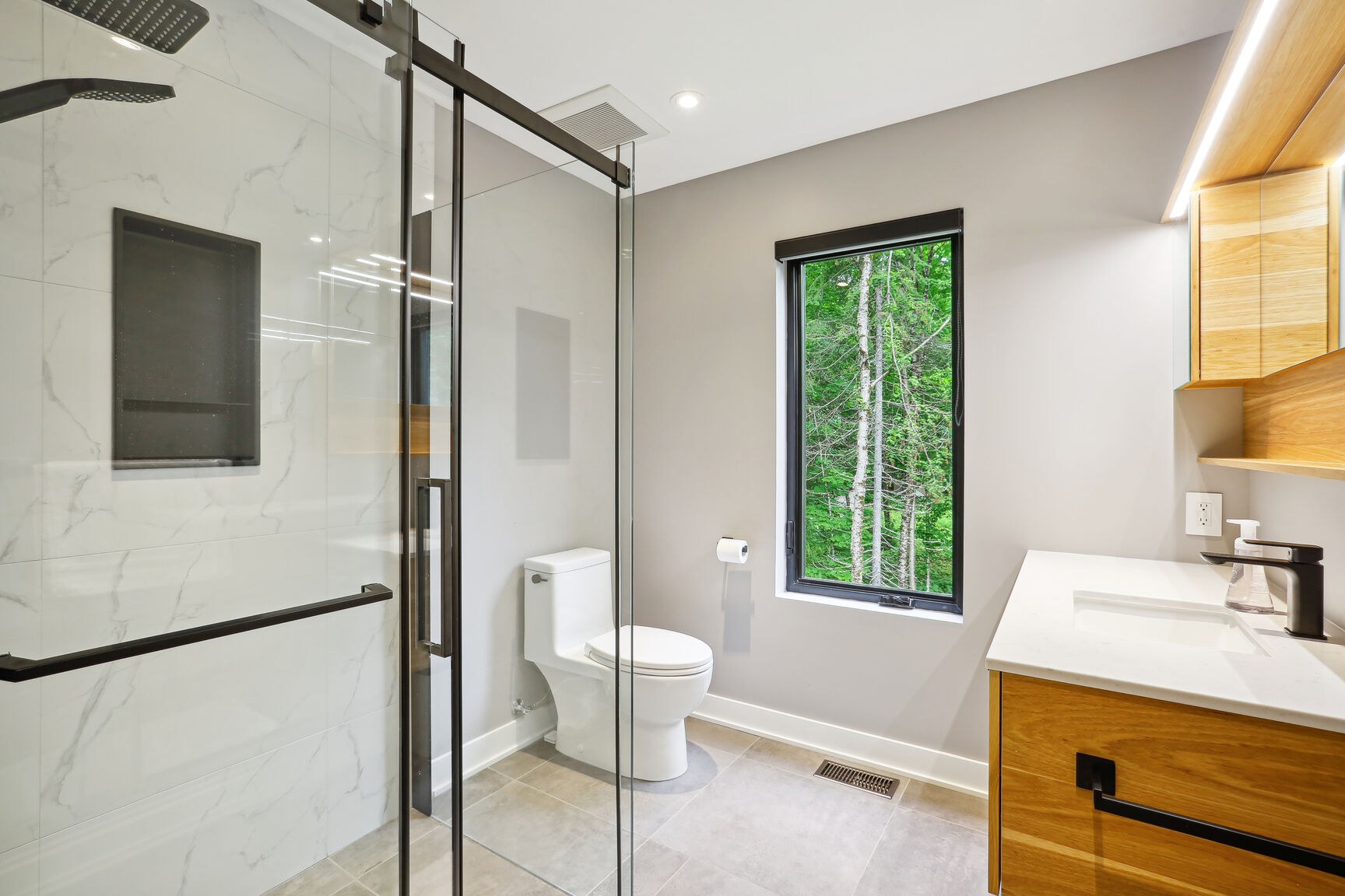 Salle de bain secondaire avec douche vitrée et fenêtre.