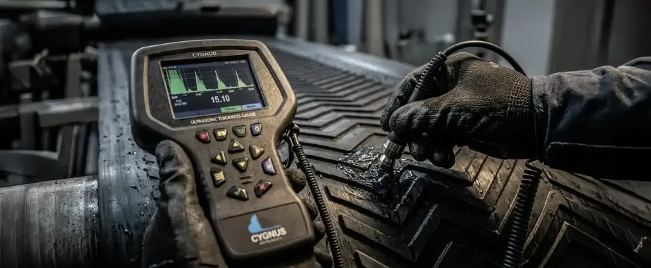 Glospech technician using Cygnus 1 EX intrinsically safe ultrasonic thickness gauge to measure wall thickness through rubber lagging on mining conveyor pulley