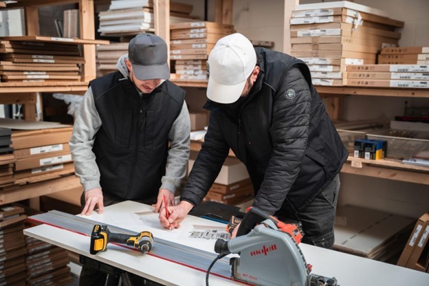 two men marking a piece of wood for cutting