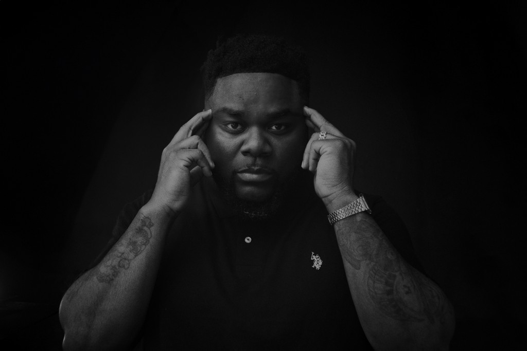 Manny XO thinking with his fingers on his temples, black and white photo.