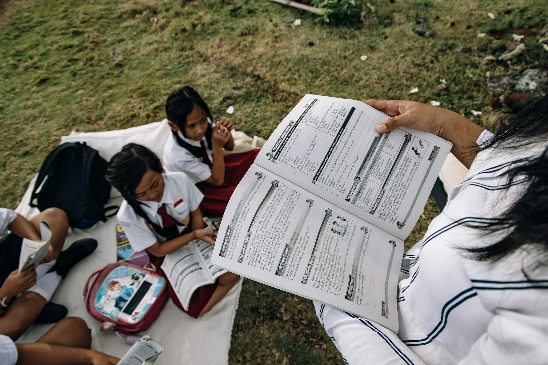 A student takes detailed notes in a spiral notebook surrounded by open reference books and colorful sticky notes.