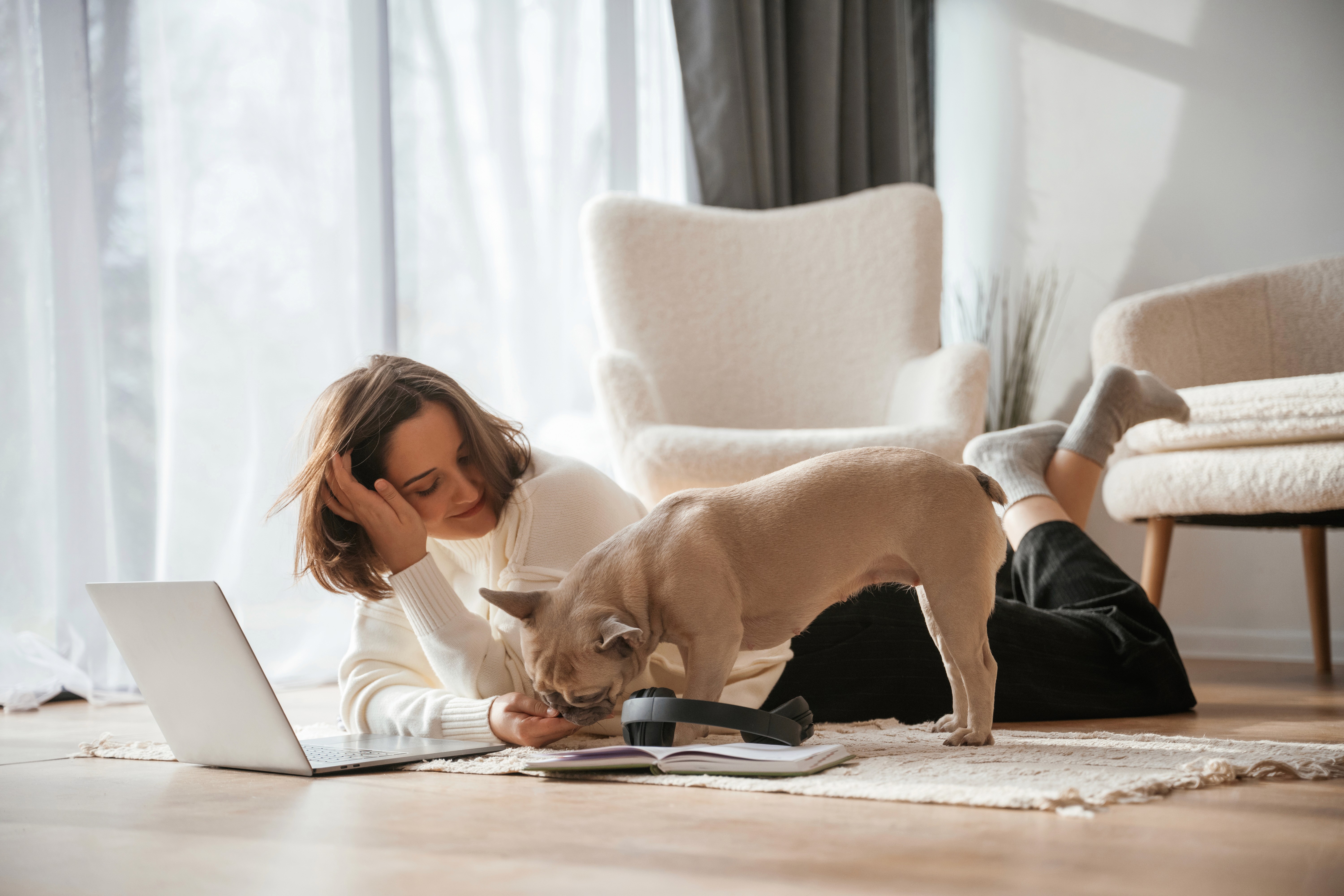 A woman relaxes and works from home while her dog plays beside her on LUXO’s light wood-look hybrid flooring. The pet-friendly, scratch-resistant surface supports modern Brisbane lifestyles, delivering comfort, durability, and easy maintenance for everyday Australian living.