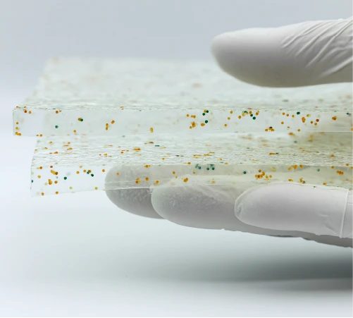 Gloved hand holding a polymer slab infused with colored microbial additive.