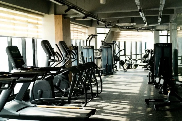 Gym floor with rows of cardio machines in daylight