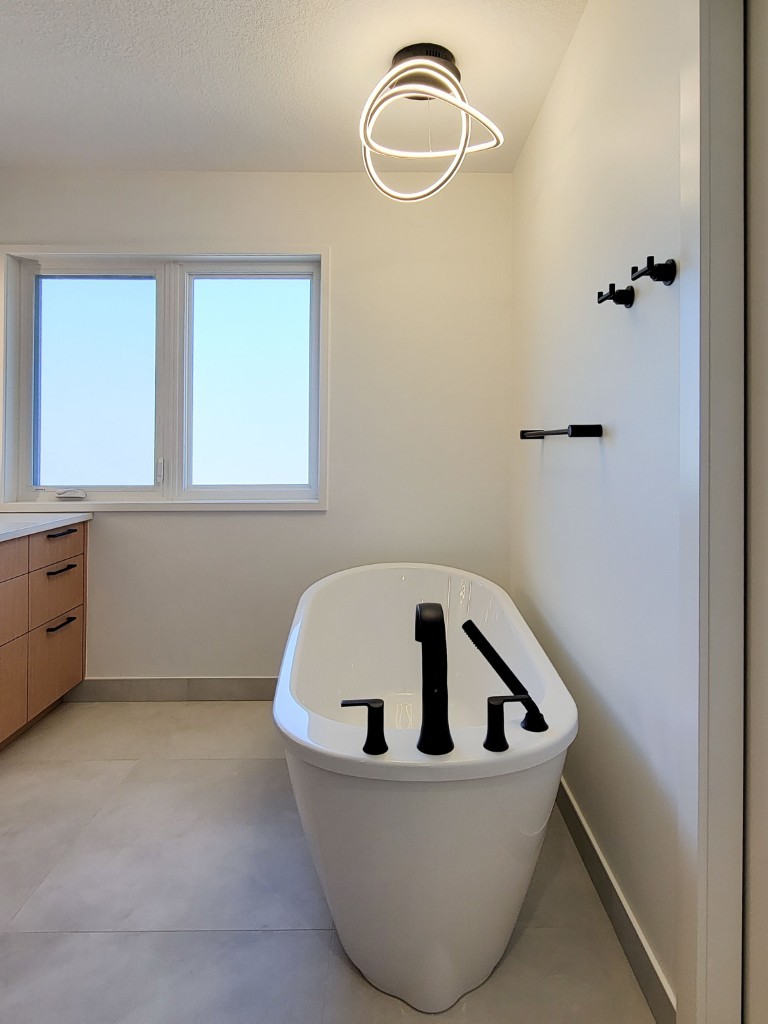 Image of Modern freestanding tub with black fixtures in a KHD Homes designed primary ensuite bathroom interior design.