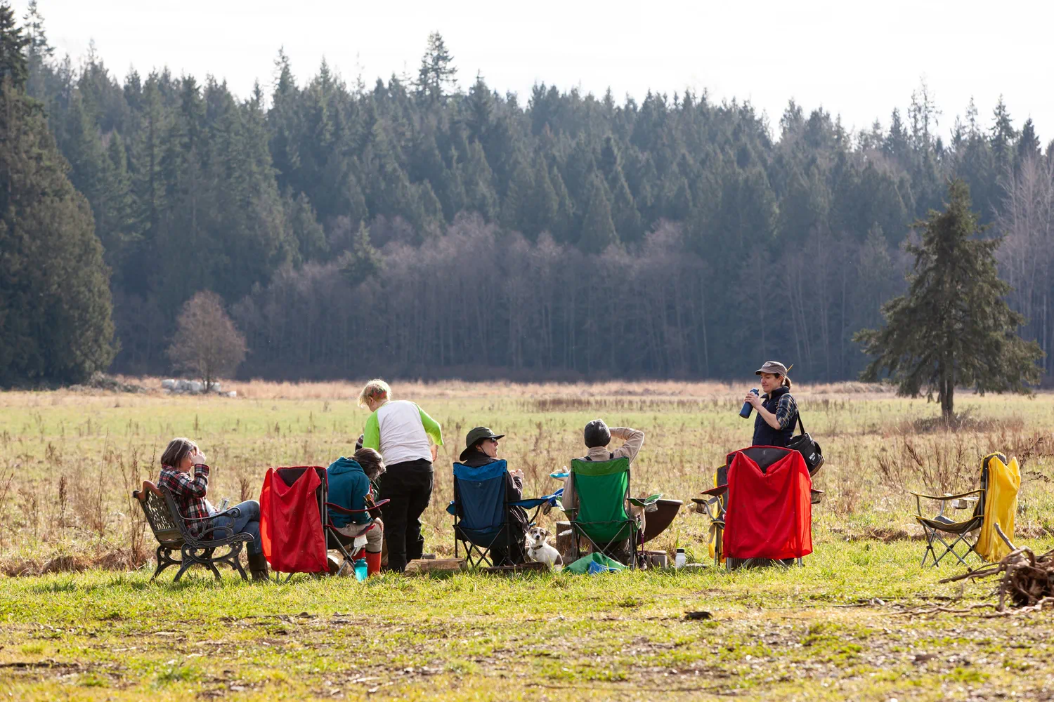 People sitting together in outdoor chairs in an open field.