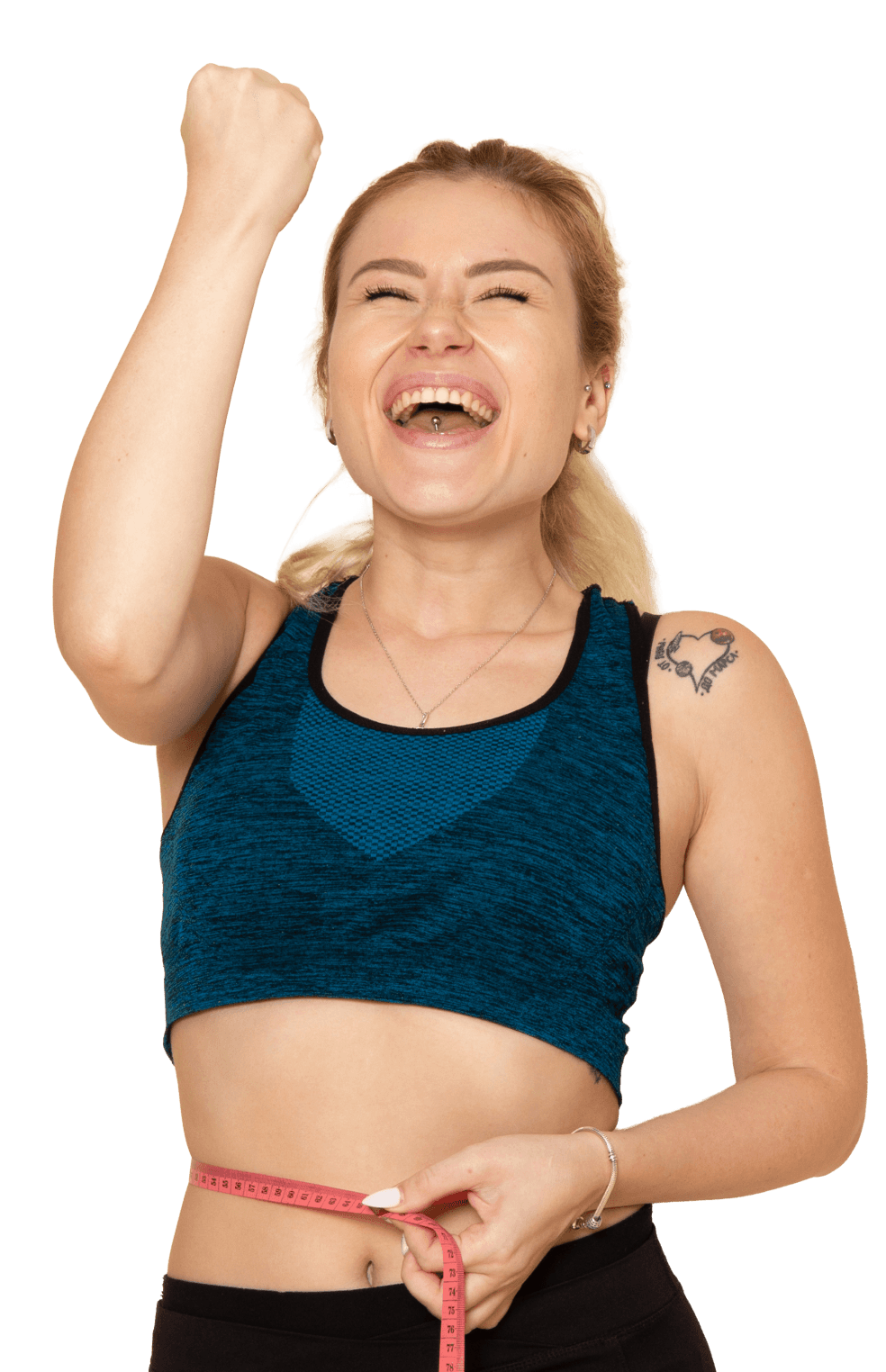 Woman celebrating with raised fist, holding a measuring tape around her waist in a sports bra