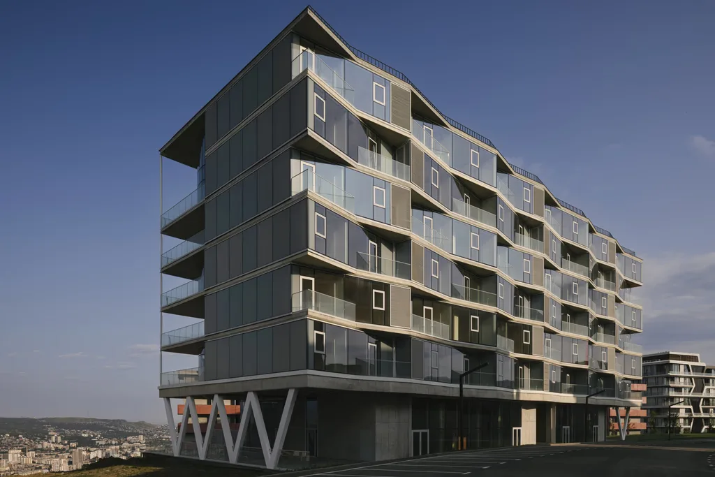 Close-up of a futuristic glass building with rounded balconies and scenic surroundings.