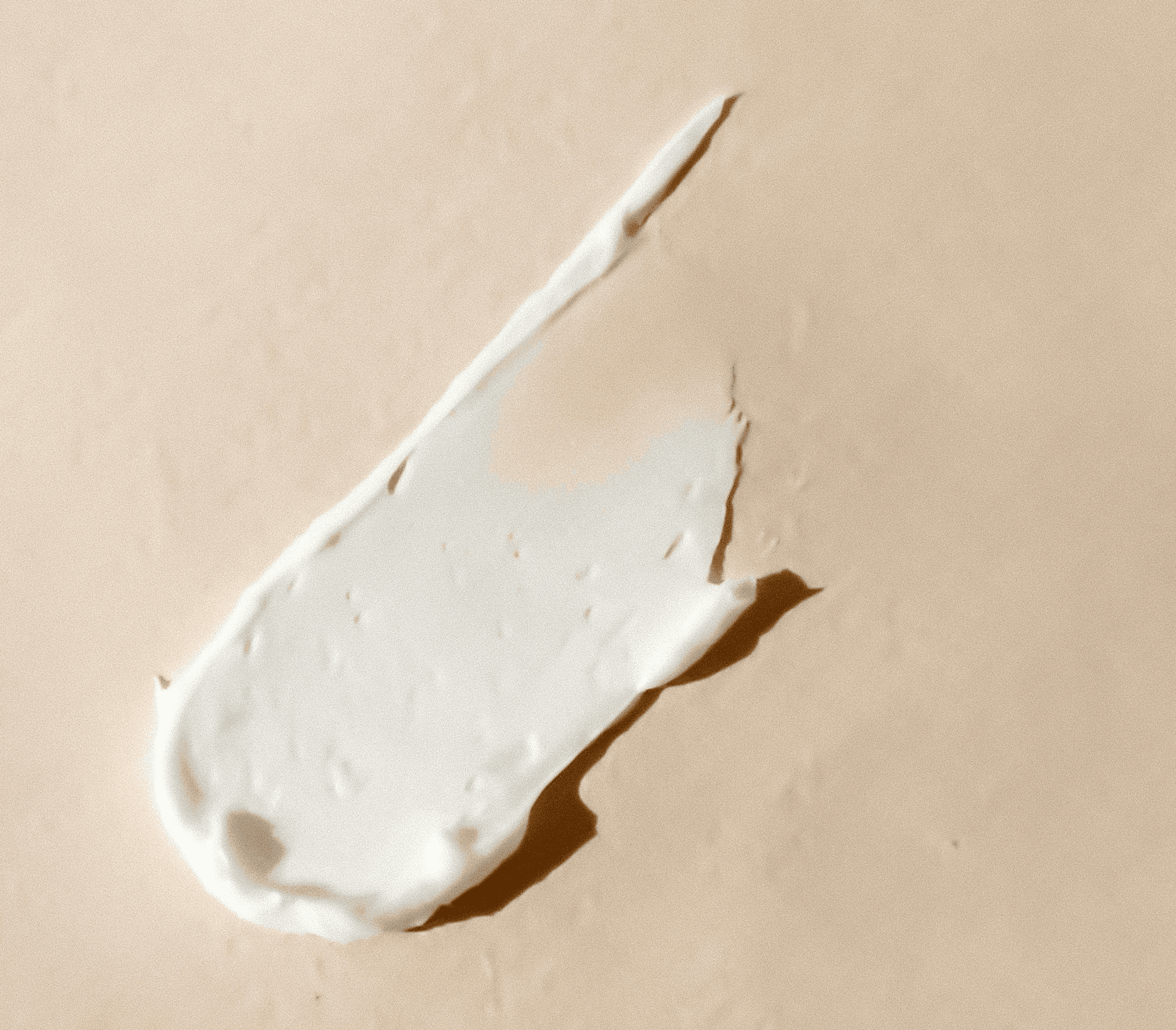 White skincare moisturiser swatch on a beige background