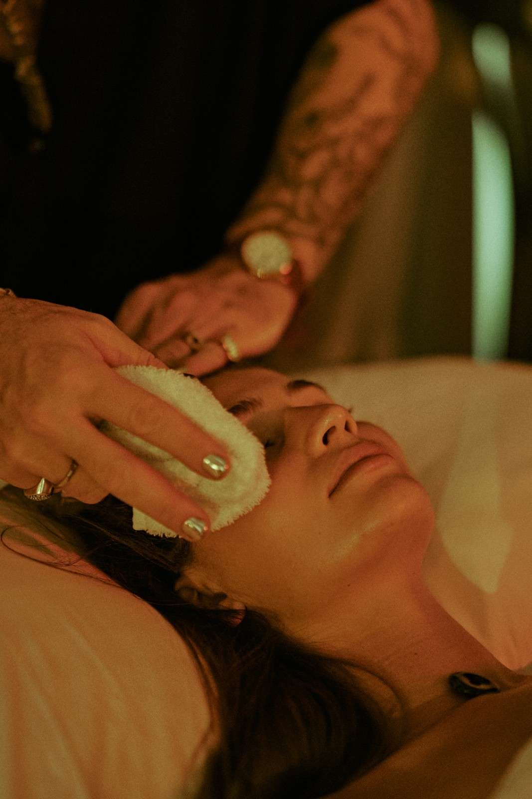 Person receiving a facial treatment with a white cloth.