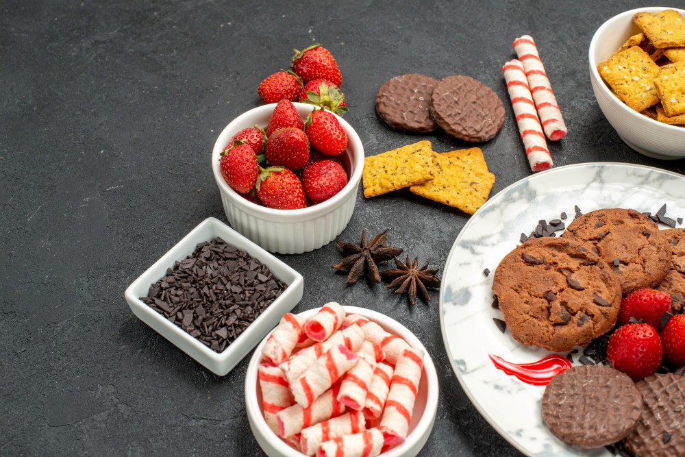 Front view choco biscuits with candies and fruits (KamranAydinov via freepik)