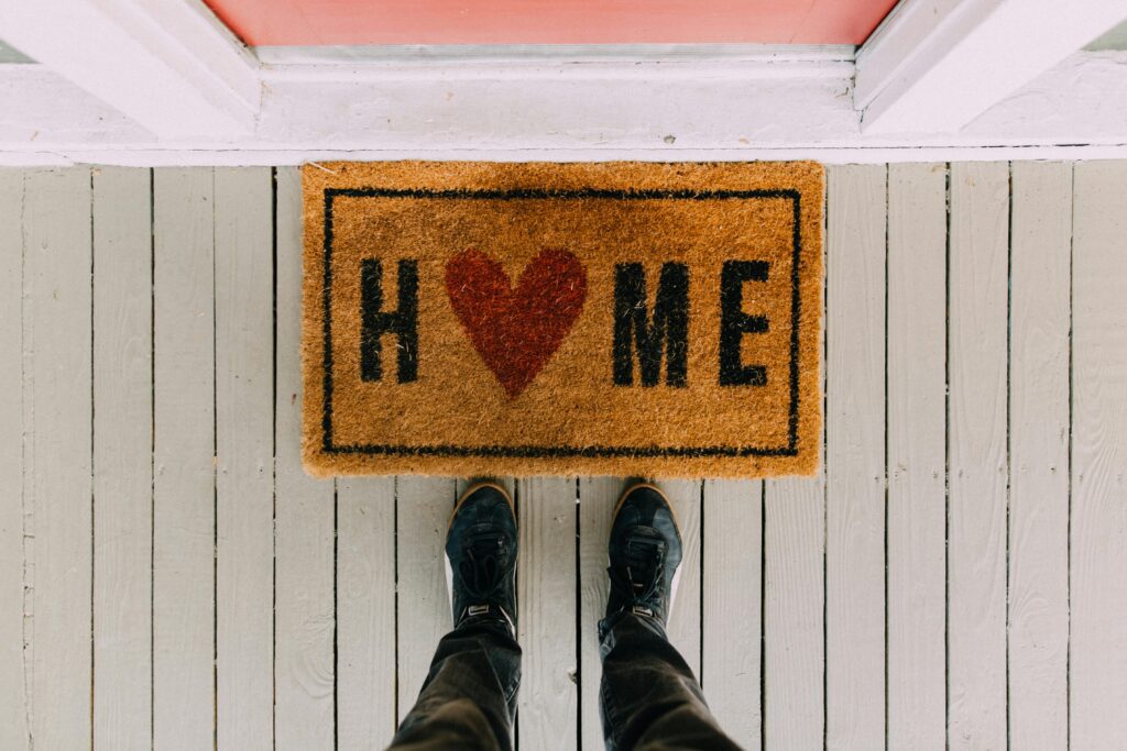 person standing in front of doormat that says 