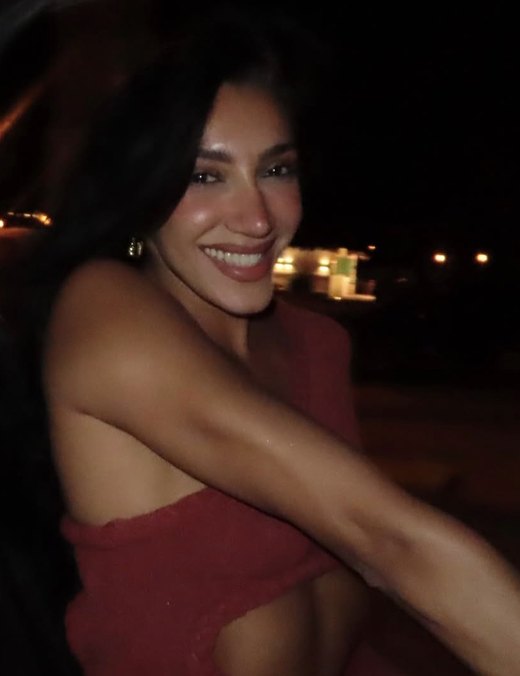 A woman in red smiling on a terrace at night
