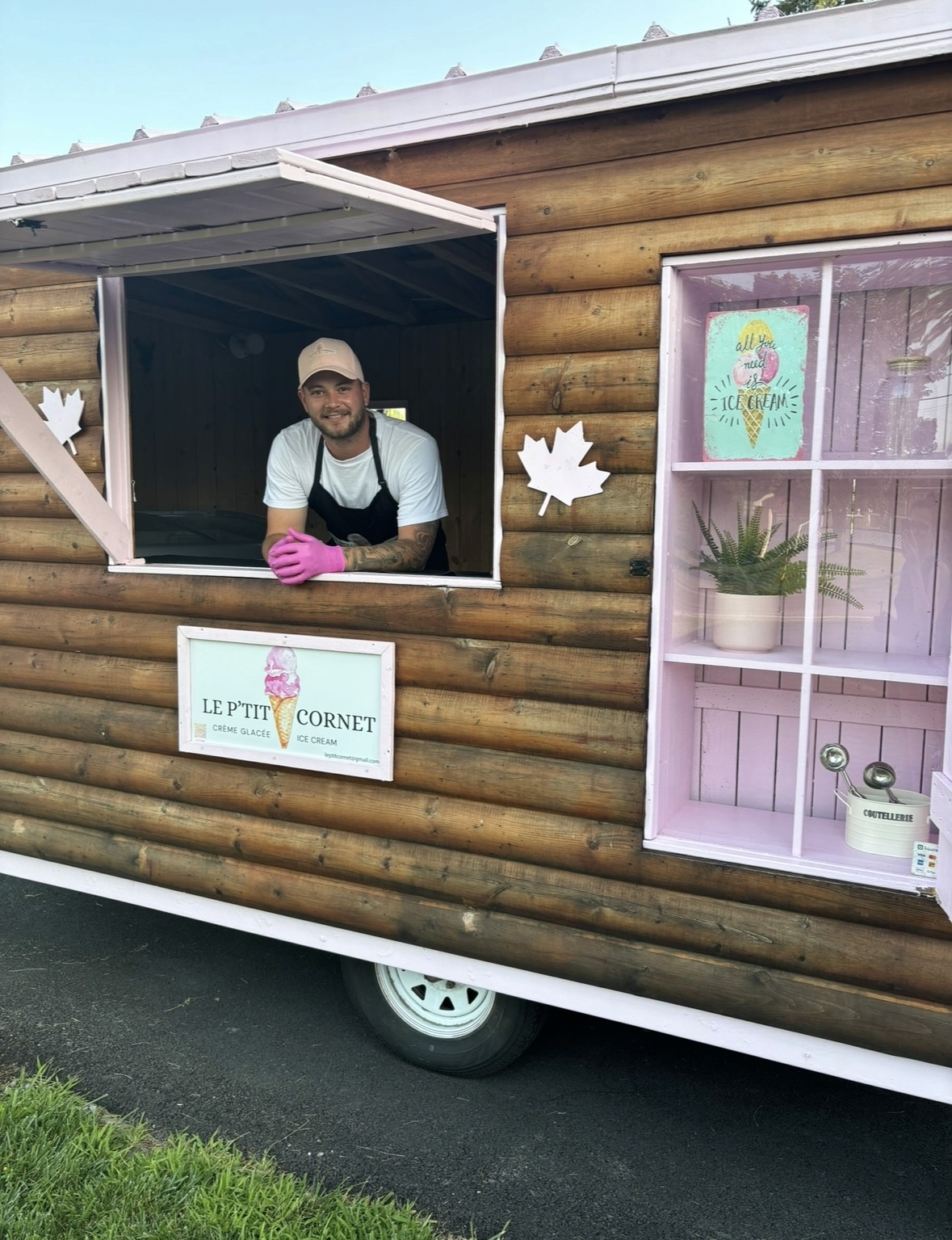 The owner of Le P'tit Cornet smiling from the window of the ice cream trailer