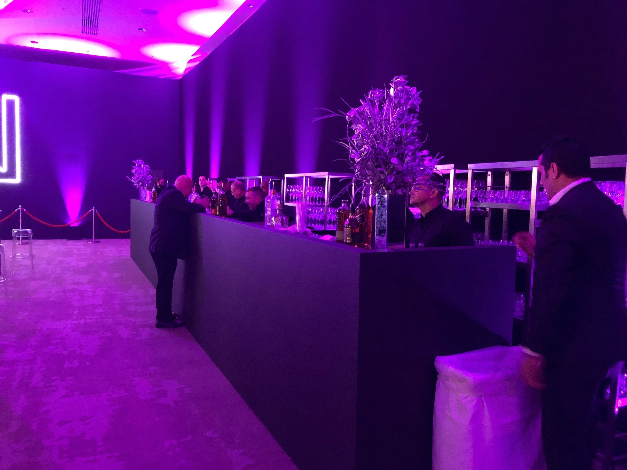 Long bar installation inside a branded event venue under purple lighting.