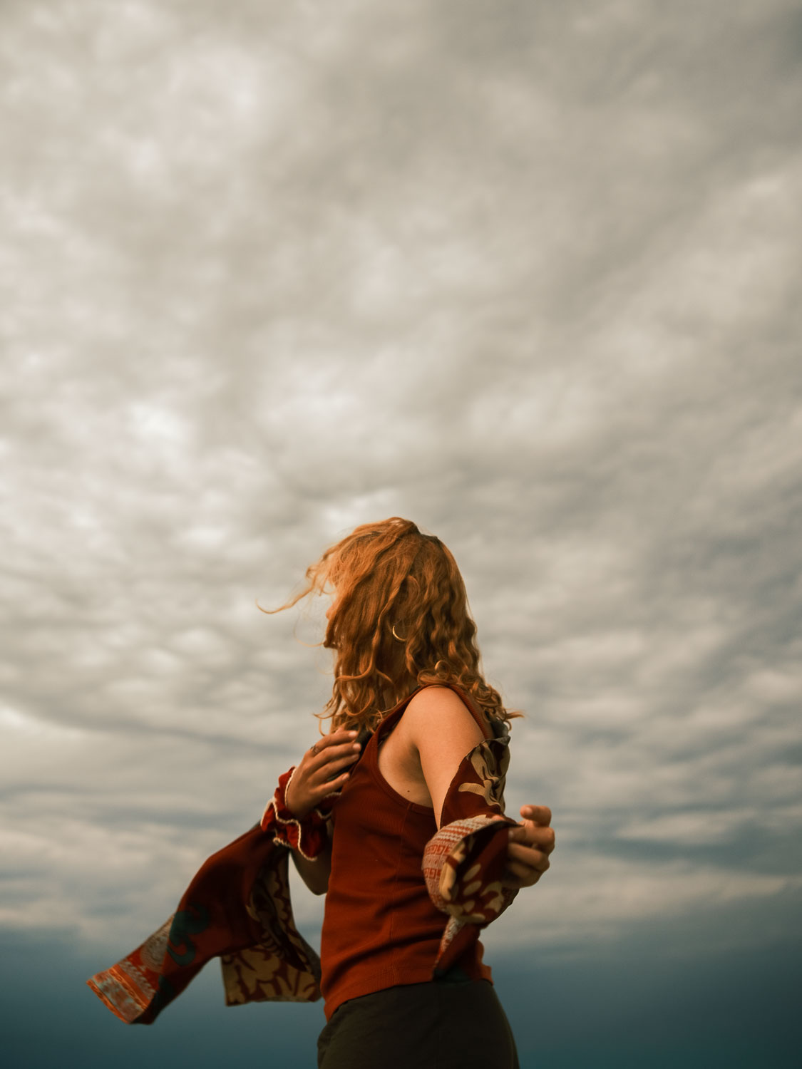 A figure in motion beneath a vast, textured sky.
