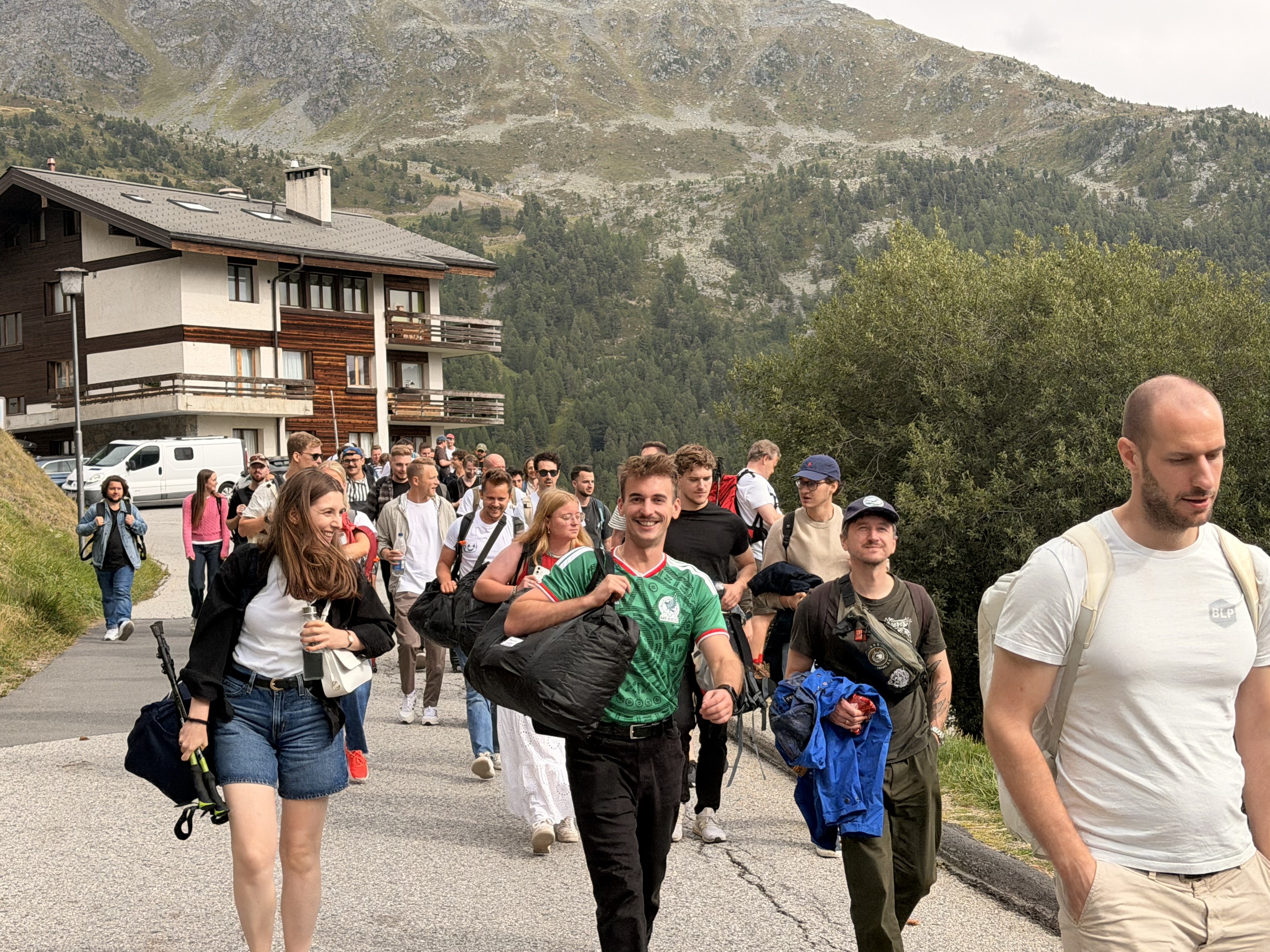 Group walking along a paved mountain path near alpine chalets.