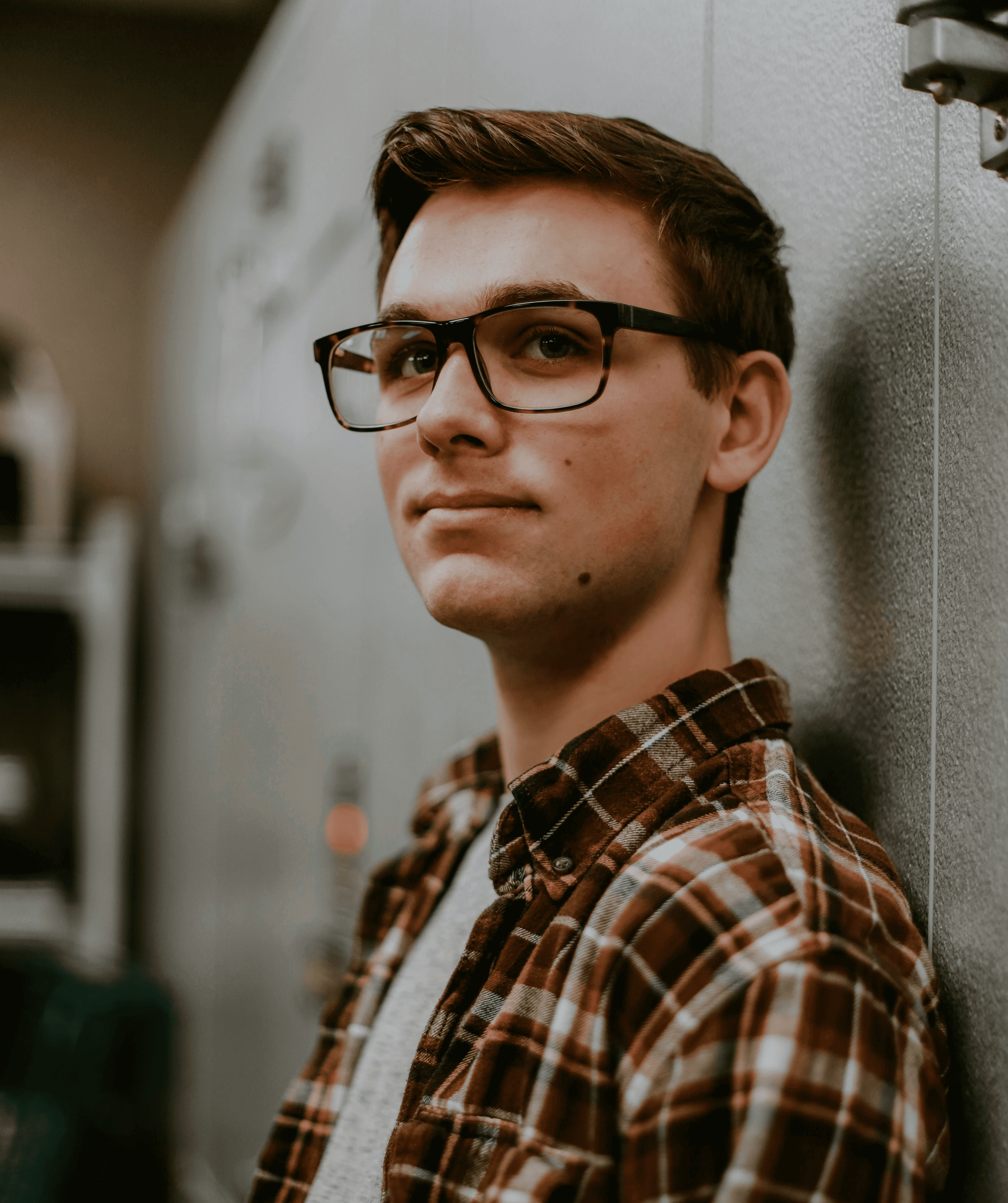 man wearing eyeglasses while leaning on wall
