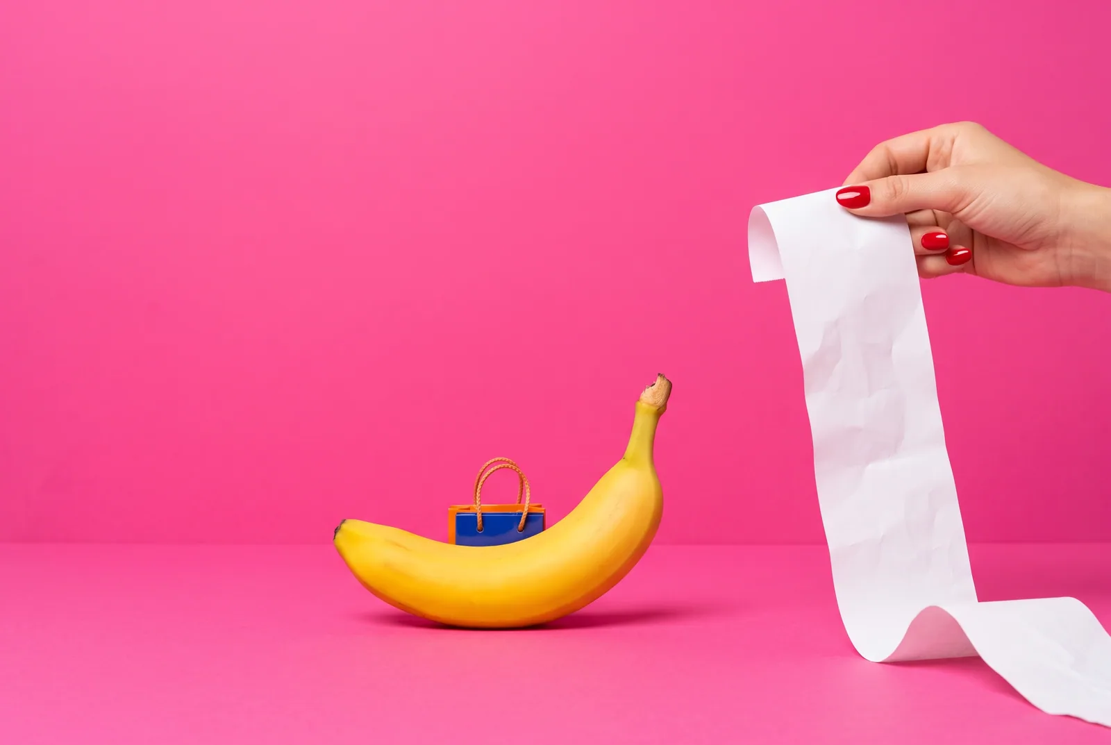 A banana hiding a tiny shopping bag as a hand holds up a long receipt, when your husband or boyfriend has an OnlyFans addiction