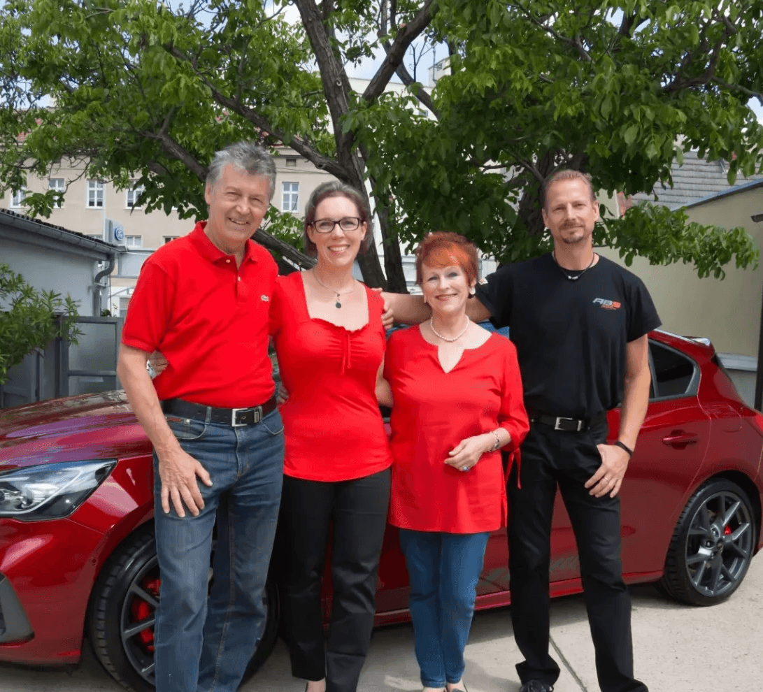 Familie Baumgartner vor einem roten Auto