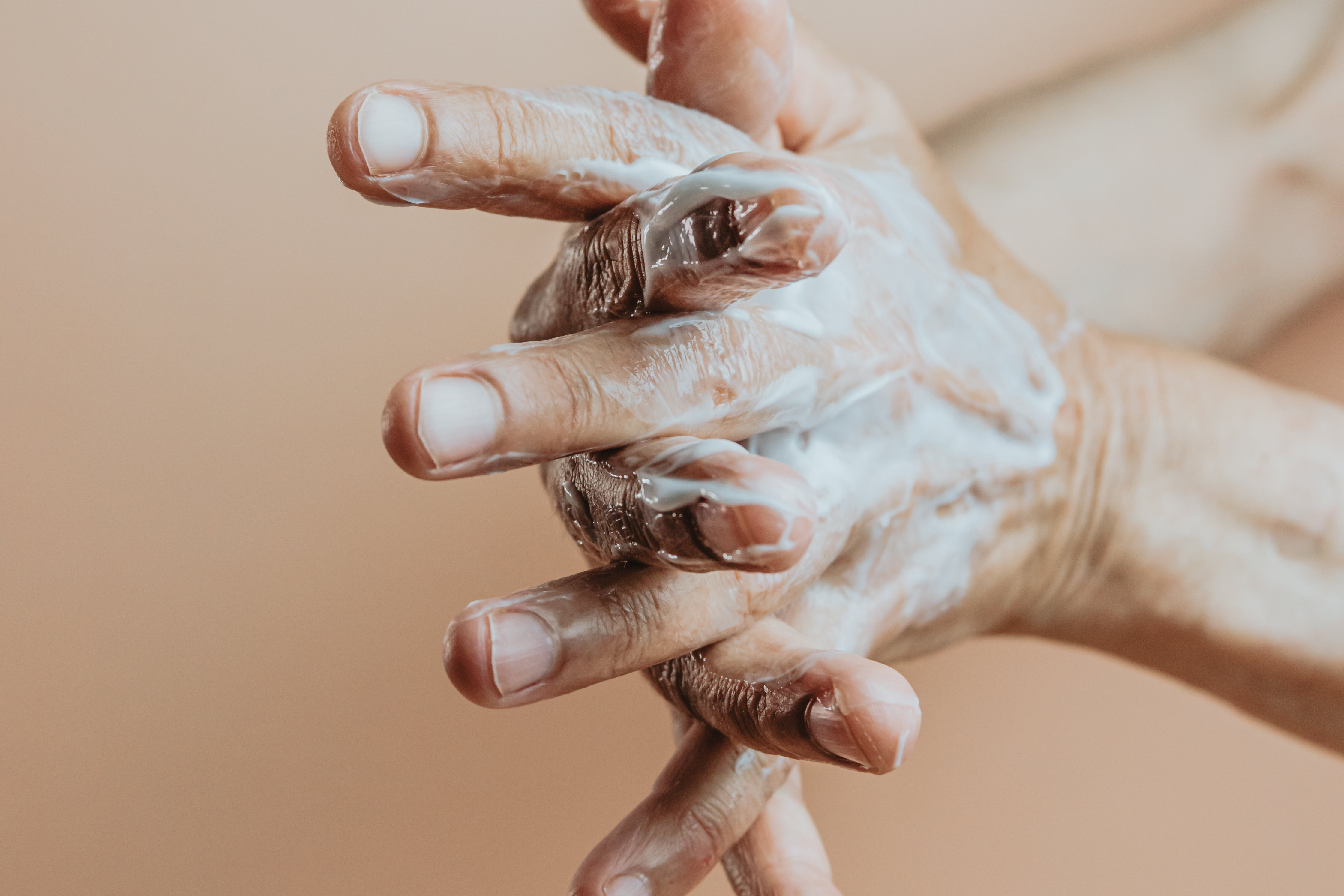 Hands lathering cream between the fingers
