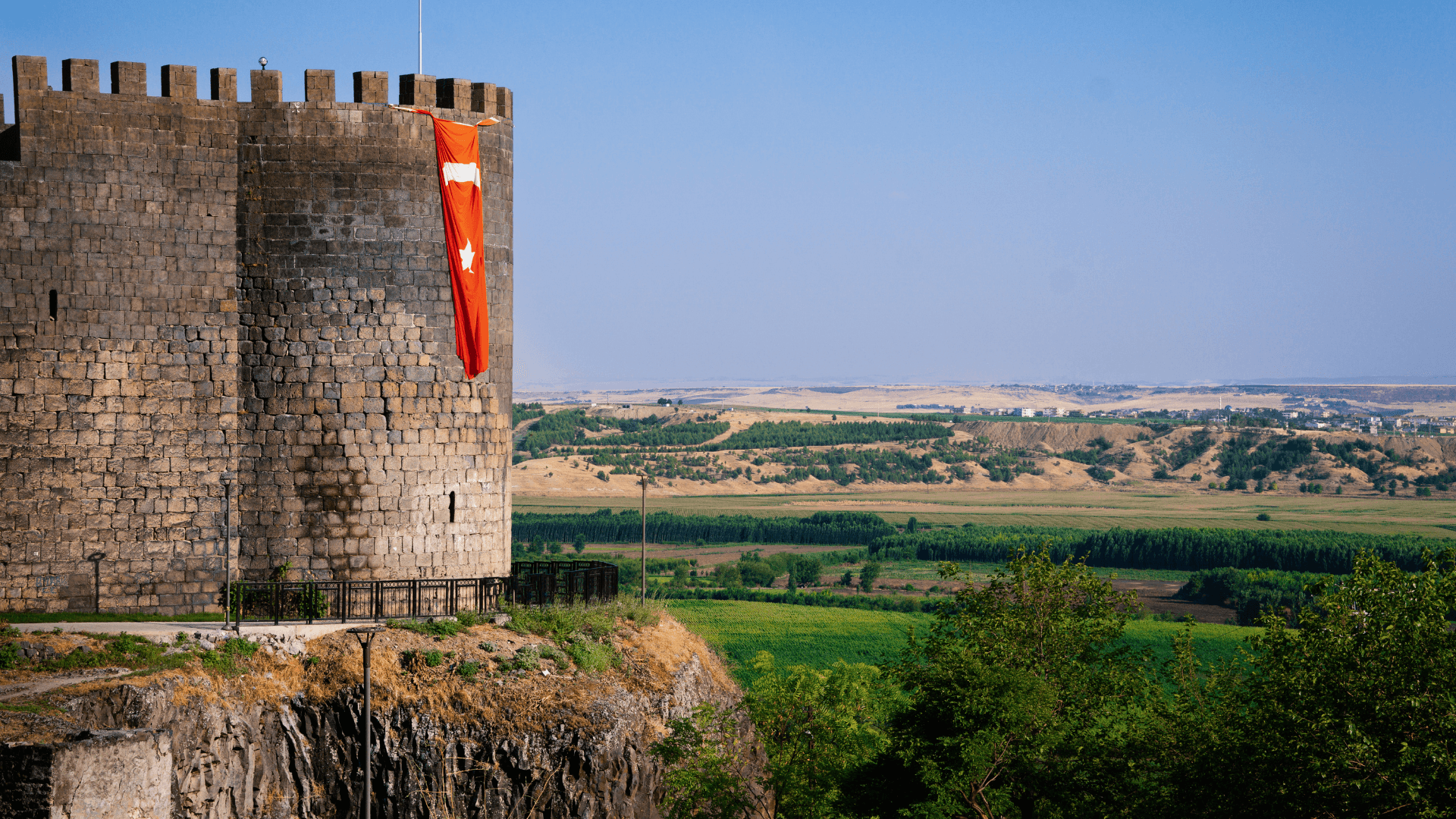 The mighty Diyarbakır Castle tower overlooking the lush UNESCO-listed Hevsel Gardens and the fertile Tigris River valley in Southeastern Türkiye.