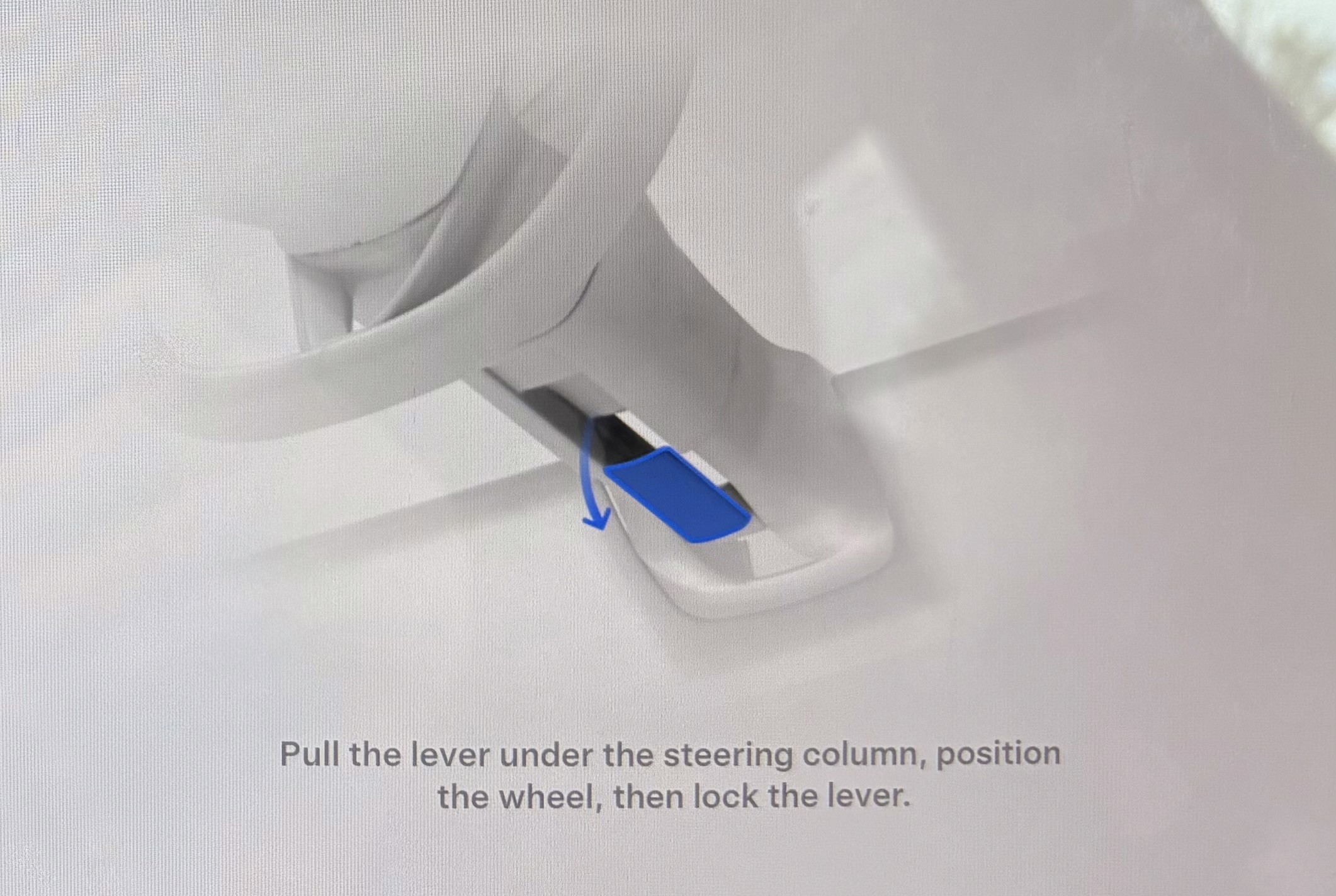 The image shows a steering column with a blue lever beneath it, accompanied by an instructional text directing to pull the lever to position and lock the steering wheel.
