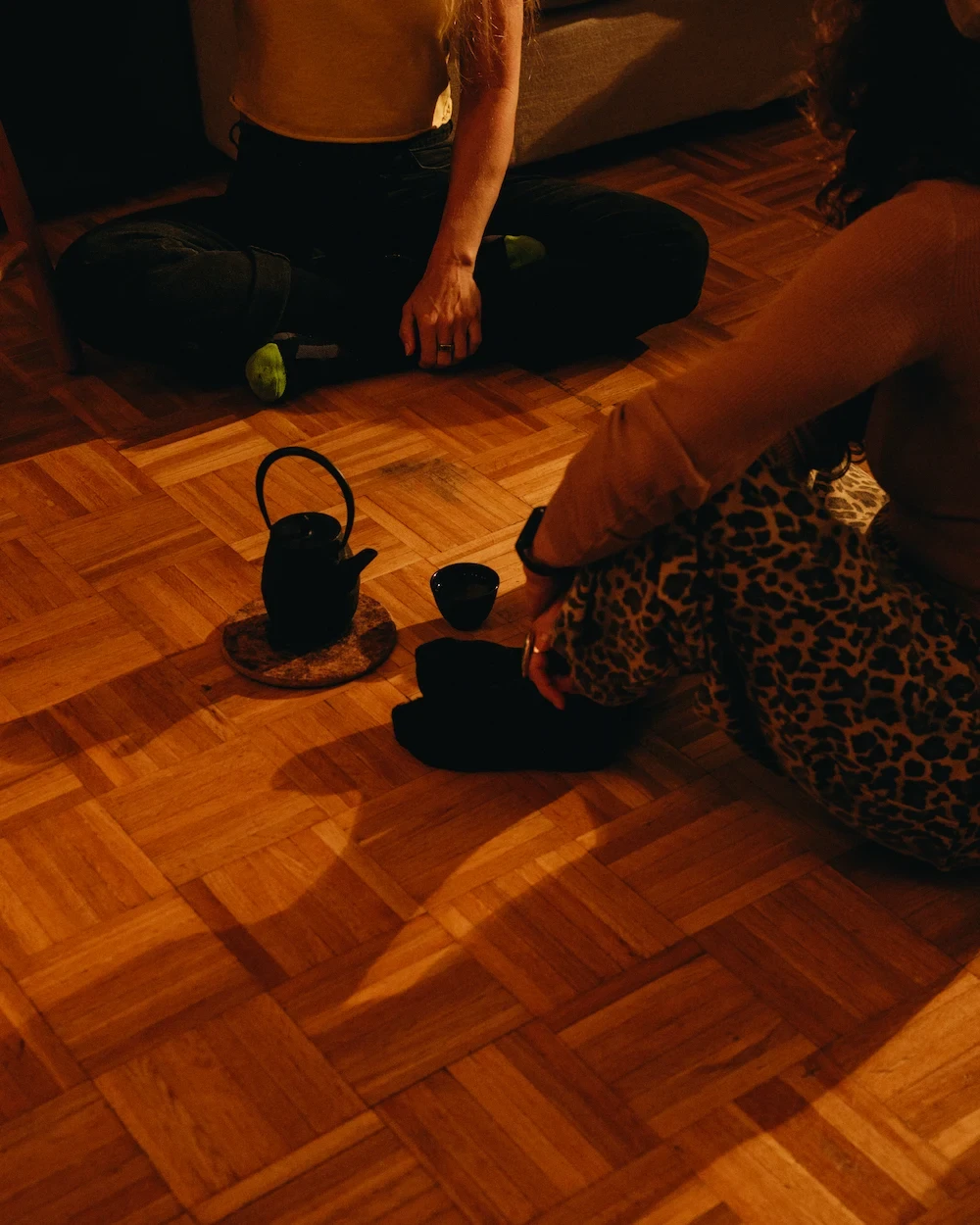 Two people seated on a wooden floor sharing tea after a sauna session in Vancouver.
