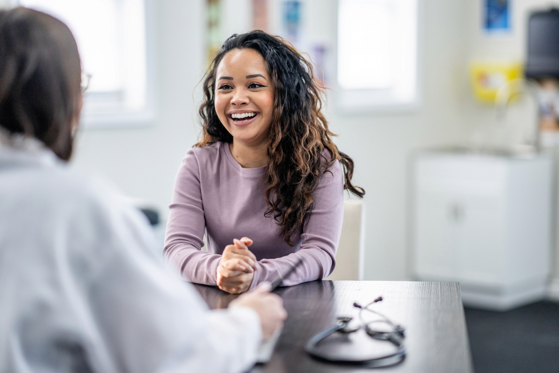 A smiling female executive sits across from a healthcare professional during a health management session